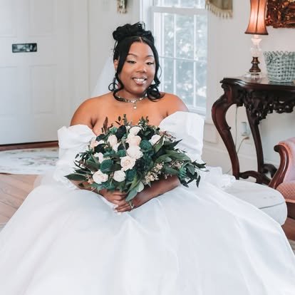 Bridal portrait of a smiling bride in a white gown holding a bouquet.