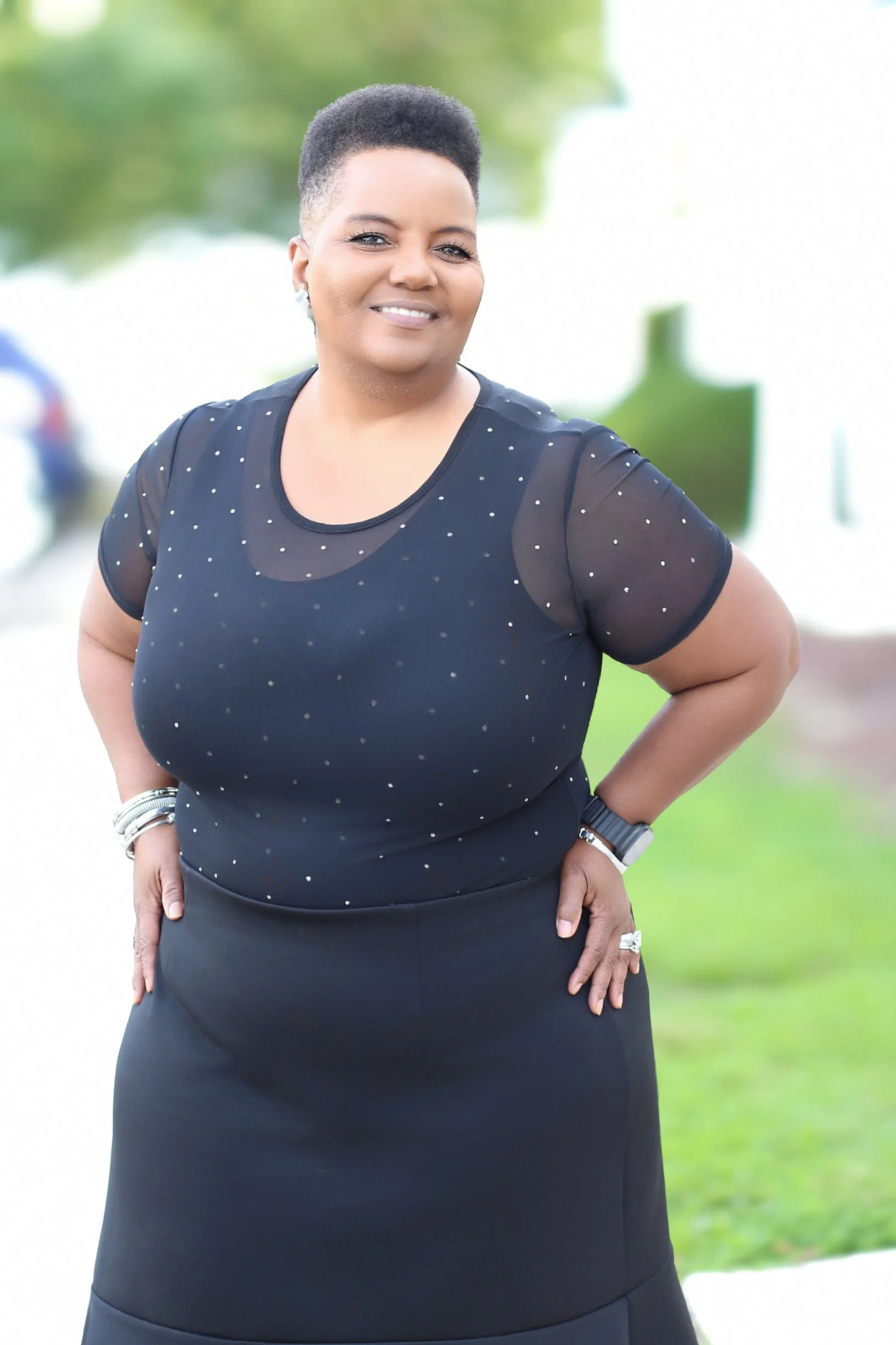 Image One Studio+ photographer Stephanie Smith smiling outdoors in a black outfit.