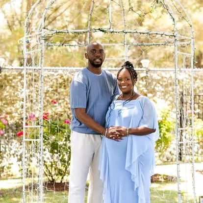 Couple posing together beneath an outdoor garden arbor.