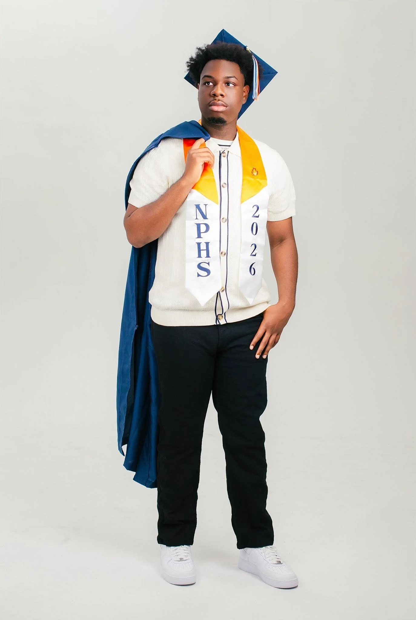 Graduate wearing a blue cap and graduation stole in a studio portrait.