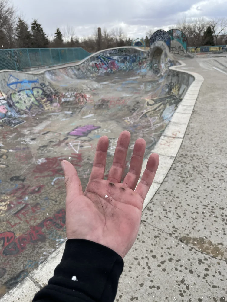 An open hand held up at the edge of a painted concrete bowl
