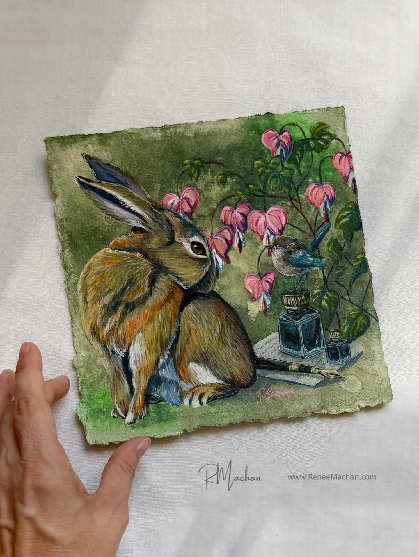 This gentle rabbit pauses beneath arching bleeding hearts, their pink blossoms glowing against the soft green backdrop. Beside him, a small blue bird perches near inkwells and pen, all symbols of stories waiting to be written. There&rsquo;s a hush to