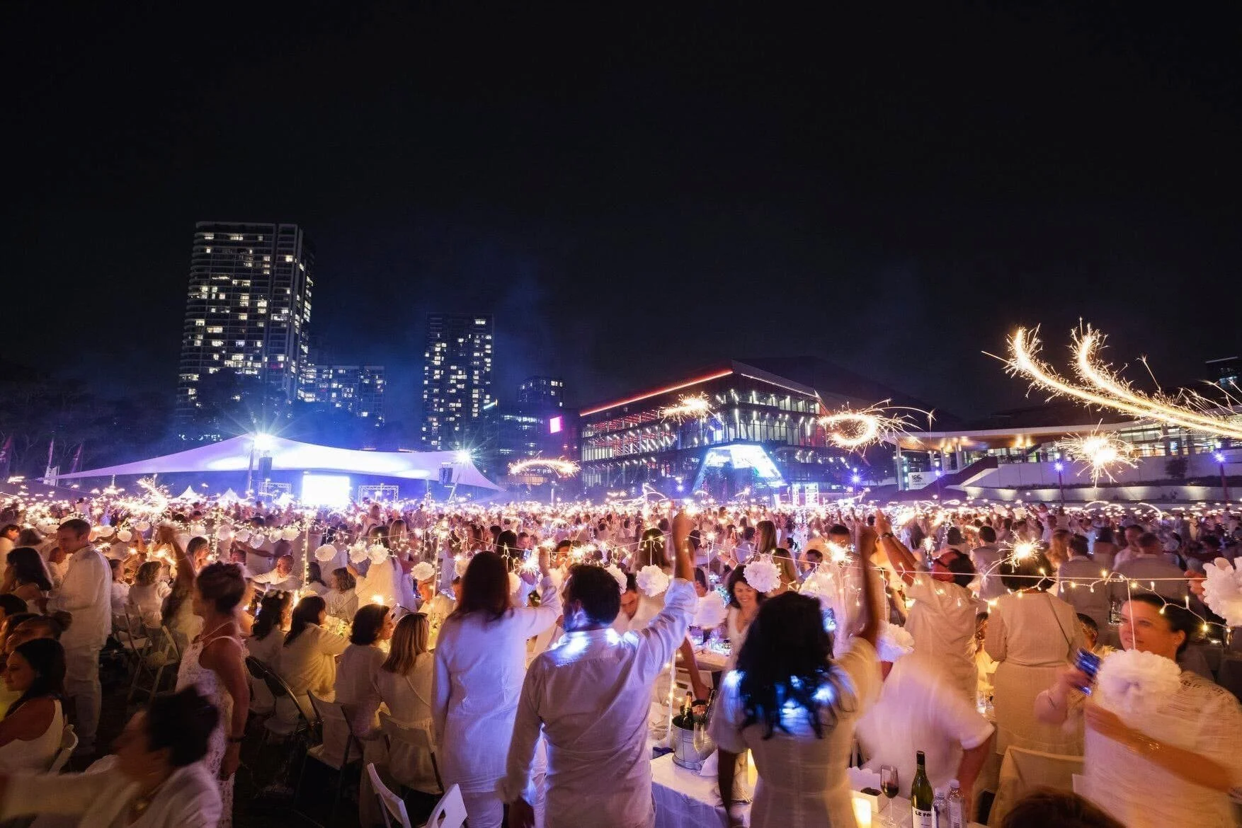 Guests dressed in white holding sparklers at Dîner en Blanc Sydney 2019, an evening event delivered by O.C.D InEvents