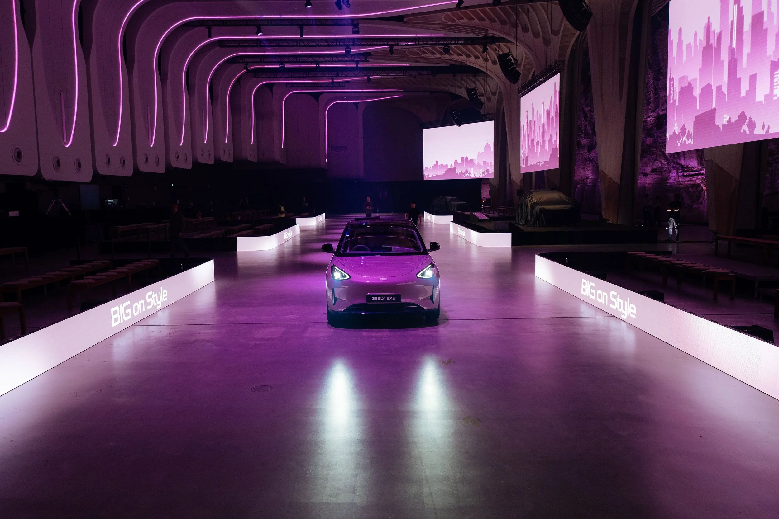 The new Geely EX2 driving down a lit runway with “BIG on Style” screens at The Cutaway