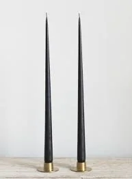 Two tall black and gold candlesticks against a plain white background.