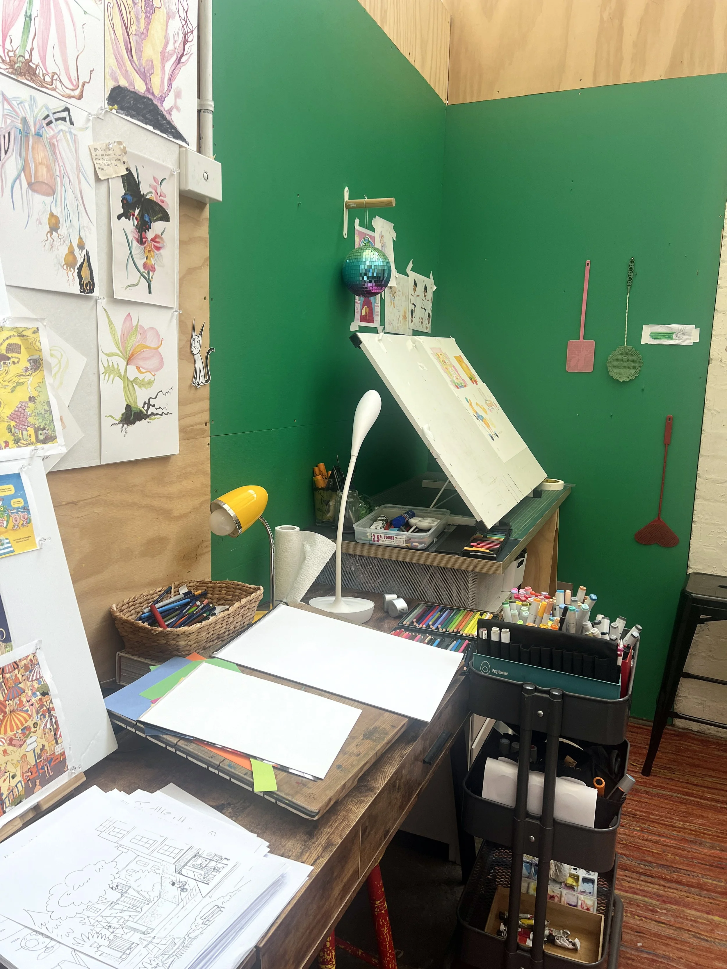This is where I do my work in pencil, paint and pen. I like to stand when I do this, and to tape my paper to the big desk on the left.