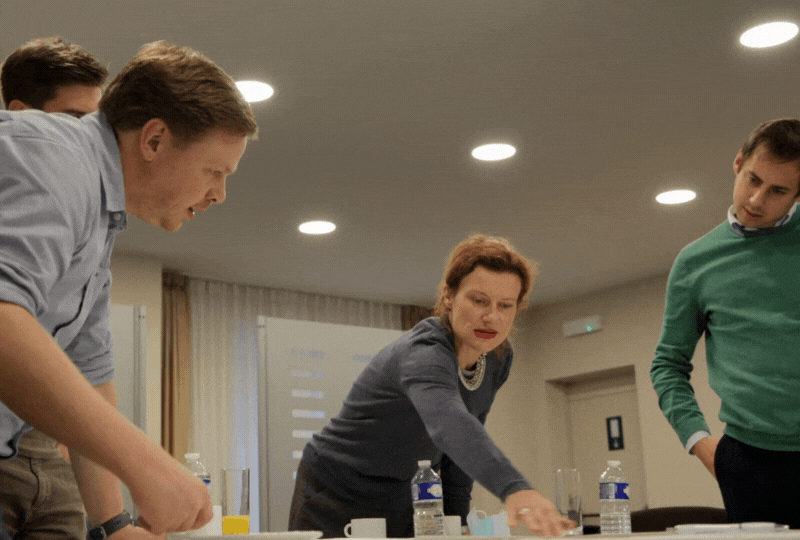 Group of people in a meeting or workshop inside a conference room, engaged in a discussion or activity.