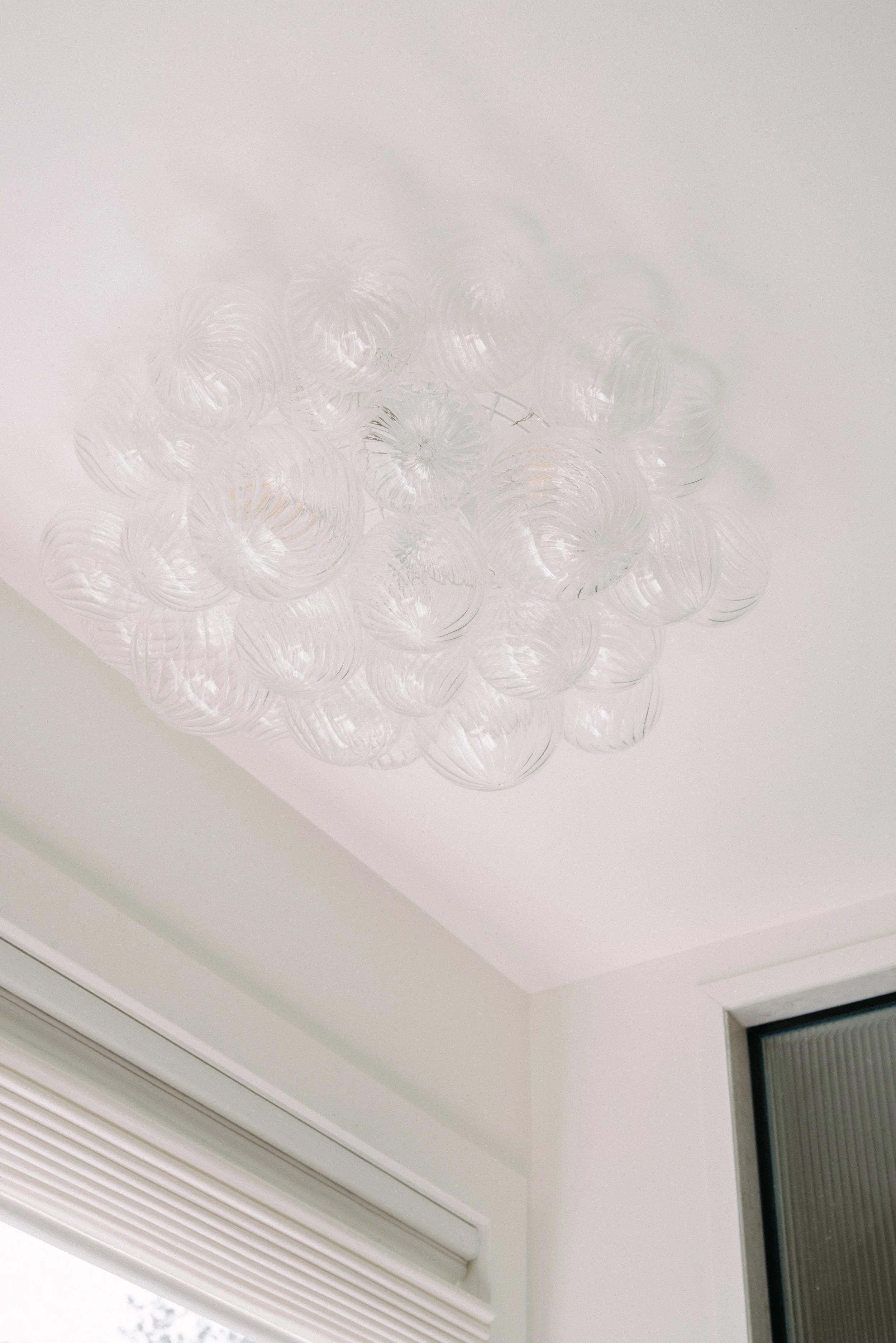 Clear glass chandelier with spherical glass shades installed on a white ceiling.