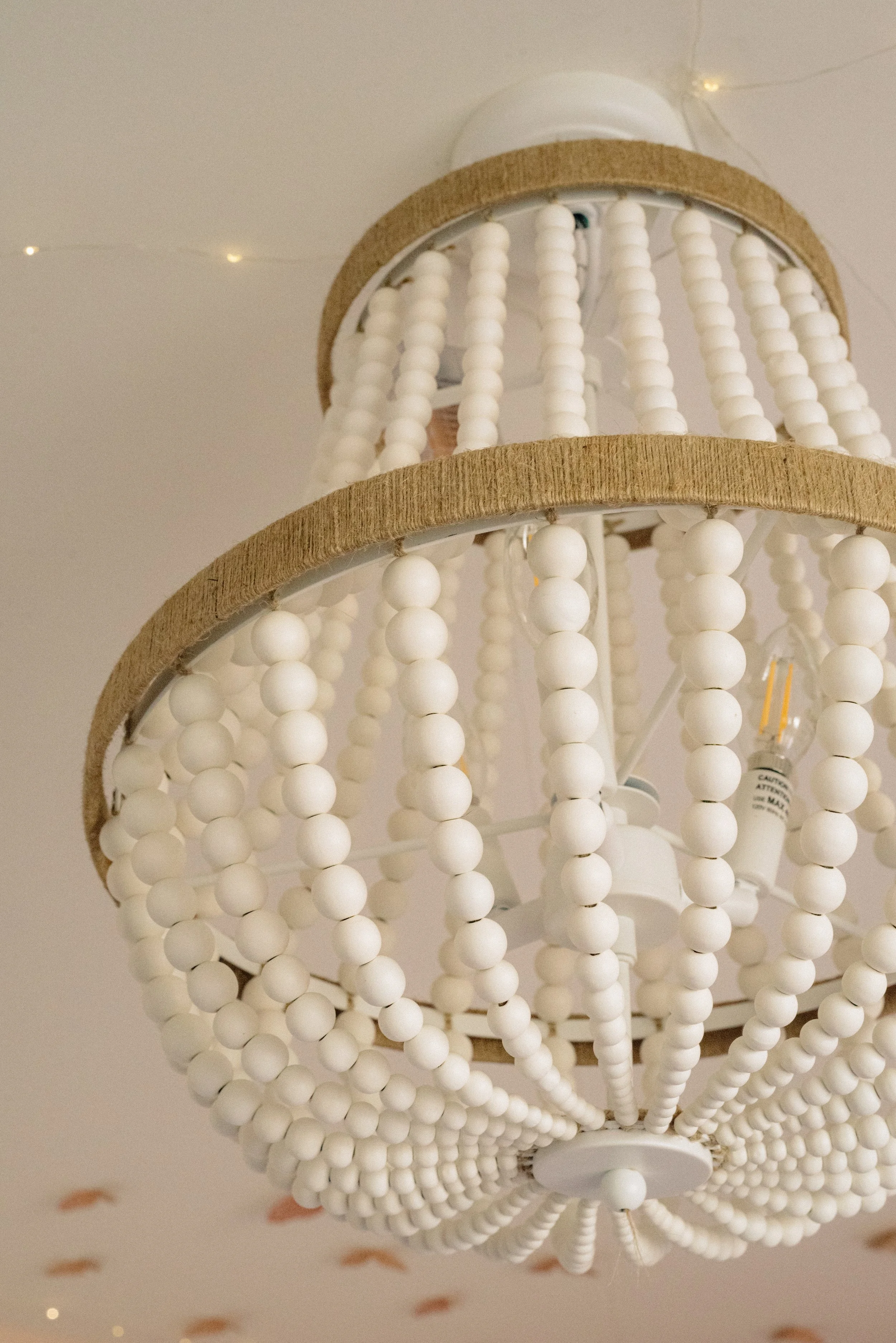 A ceiling light fixture with globe-shaped bulbs and bead-like decorative elements.