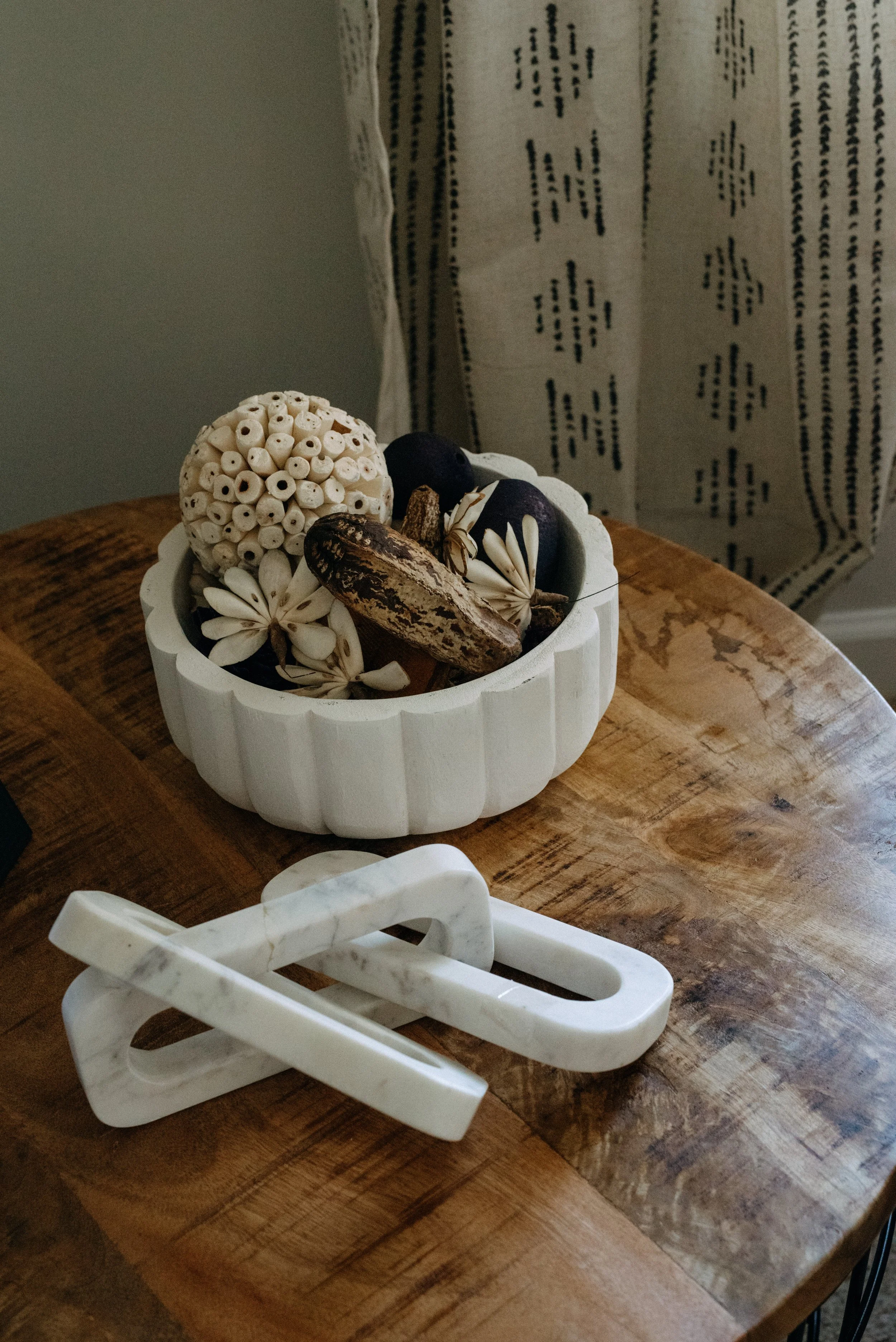 Decorative bowl with dried flowers, pine cones, and other natural elements on a wooden table.