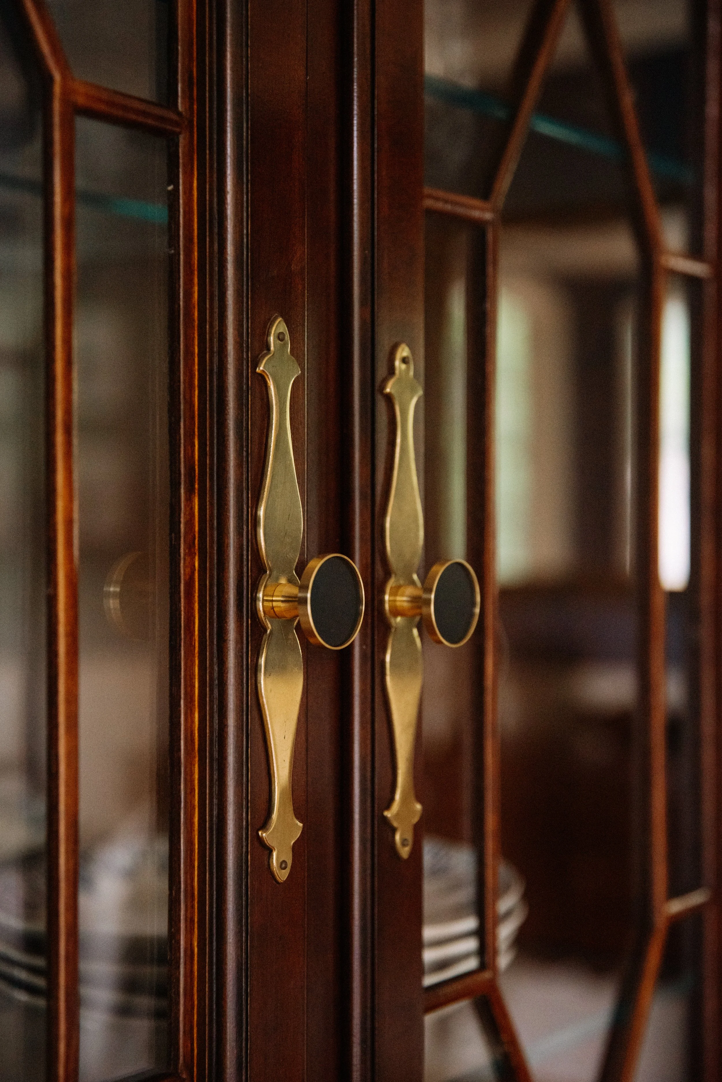 Close-up of wooden cabinet with glass doors and brass handles.