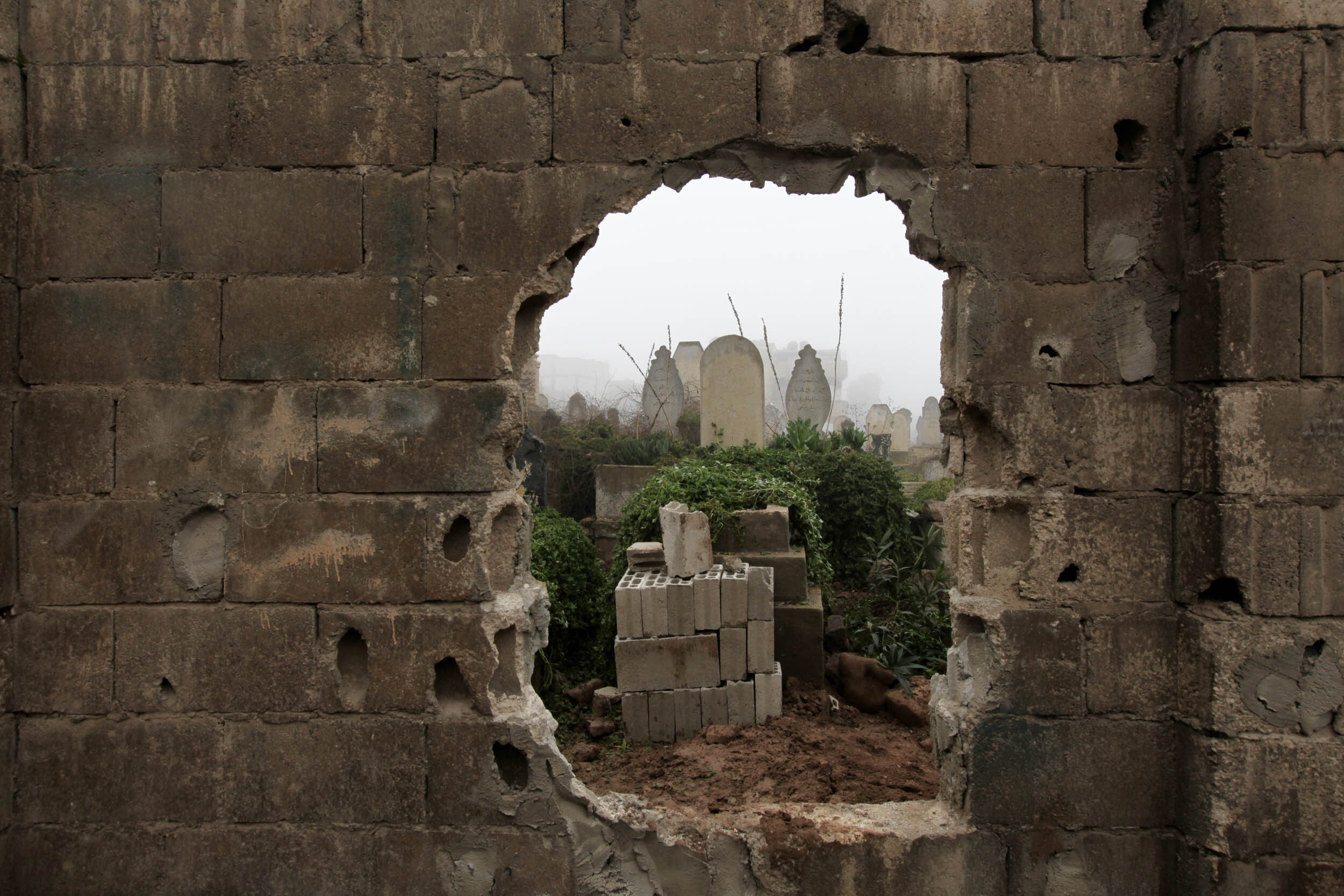  To avoid the main gate exposed to sniper fire, residents pierced a hole in the cemetery wall, Bab Drib, Homs, Jan 26/2012. 