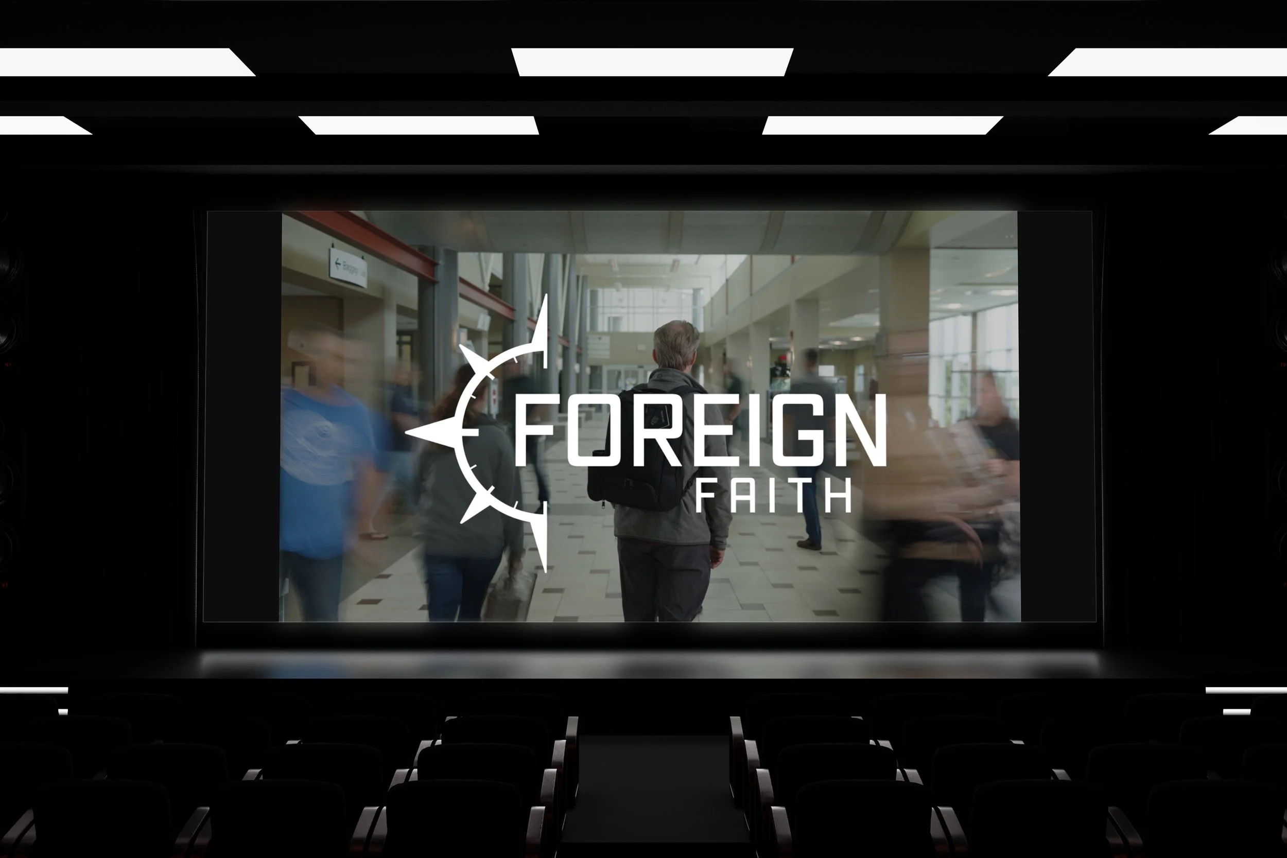 A large movie theater screen displays an image of a man walking through an airport terminal with the overlayed text "FOREIGN FAITH" and a compass logo.