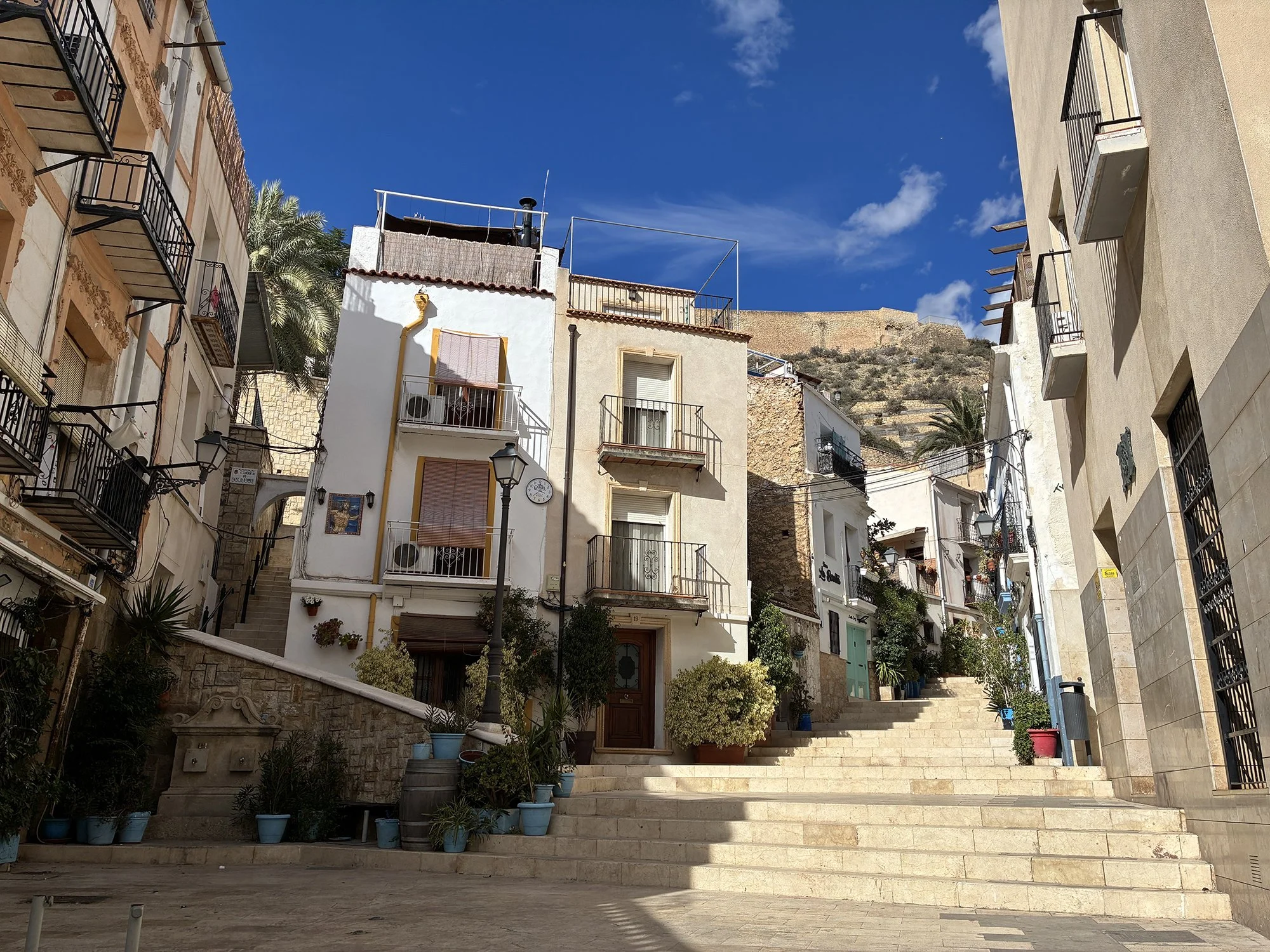 A quiet street in Alicante, Spain, with stairs ascending to a building, showcasing the city's hidden charm.