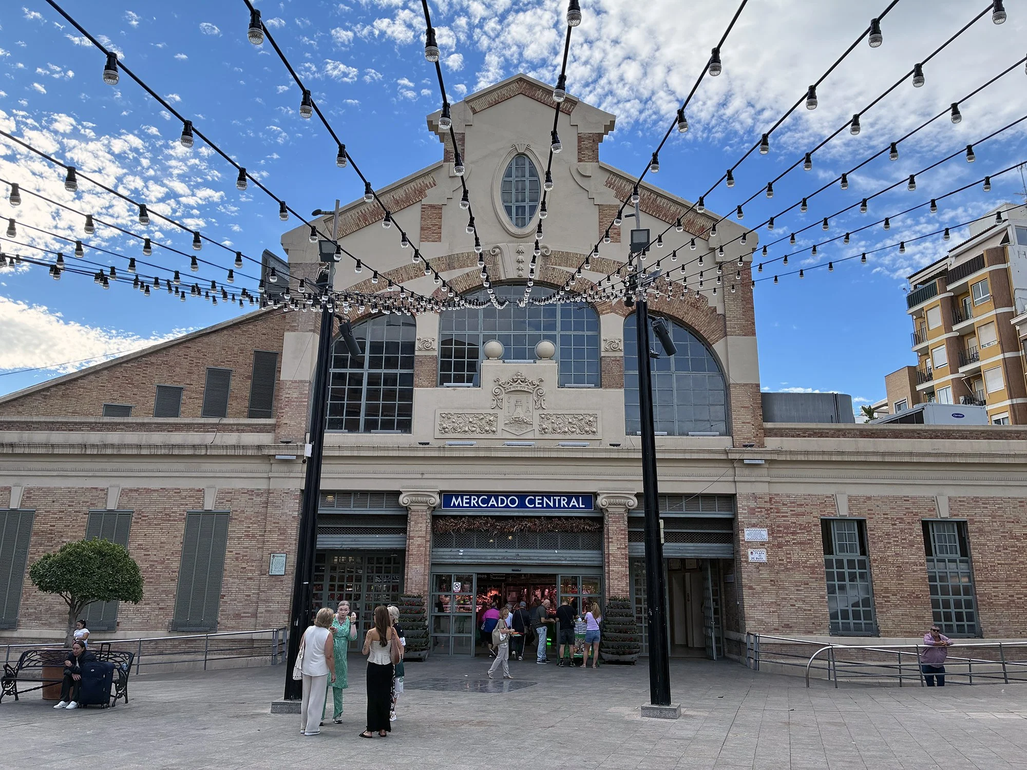 A group of people walks leisurely around mercado central in Alicante, Spain, showcasing the city's charming, less-visited areas.