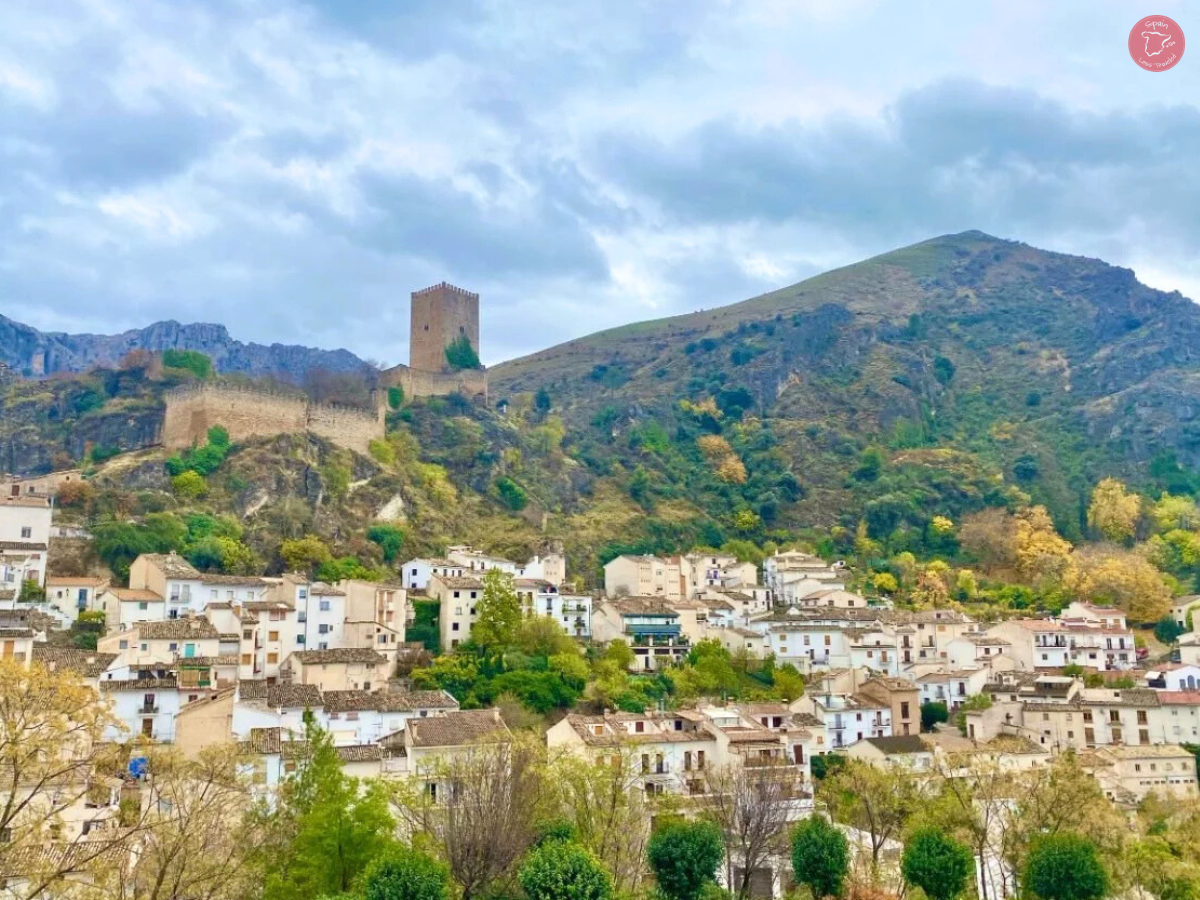 Buildings in Cazorla, with a castle in the background perched on a hill.