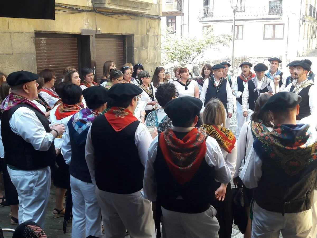 A group of people standing in a circle, wearing traditional Euskal Jaiak clothing.