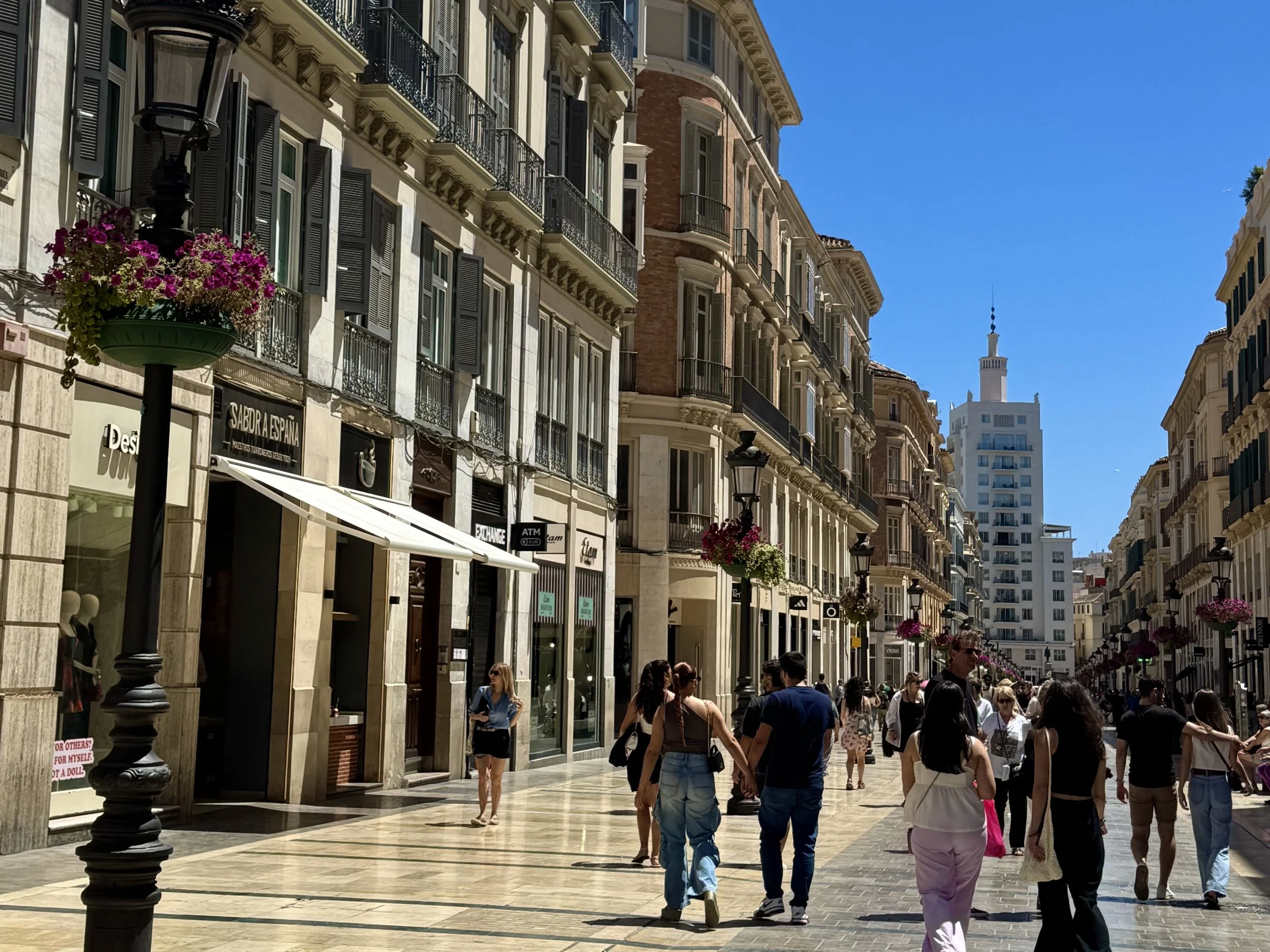 A group of people stroll down Larios street in Malaga, Spain, surrounded by charming city architecture.