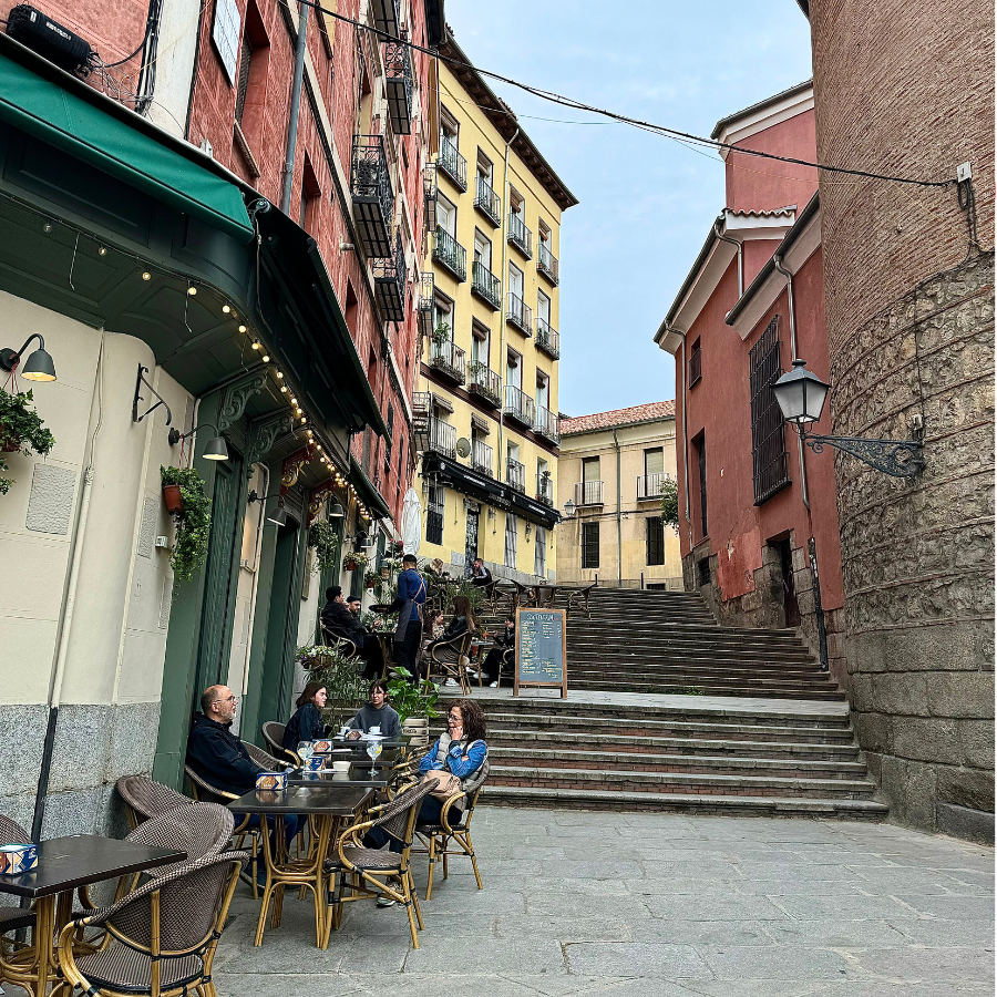 People enjoying coffee and conversation at tables in an outdoor cafe in La Latina, Madrid.