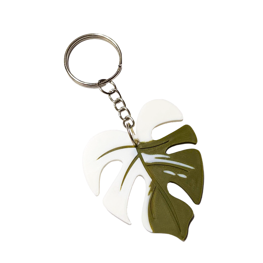 A leaf-shaped keychain with white and olive green sections, attached to a metal keyring.
