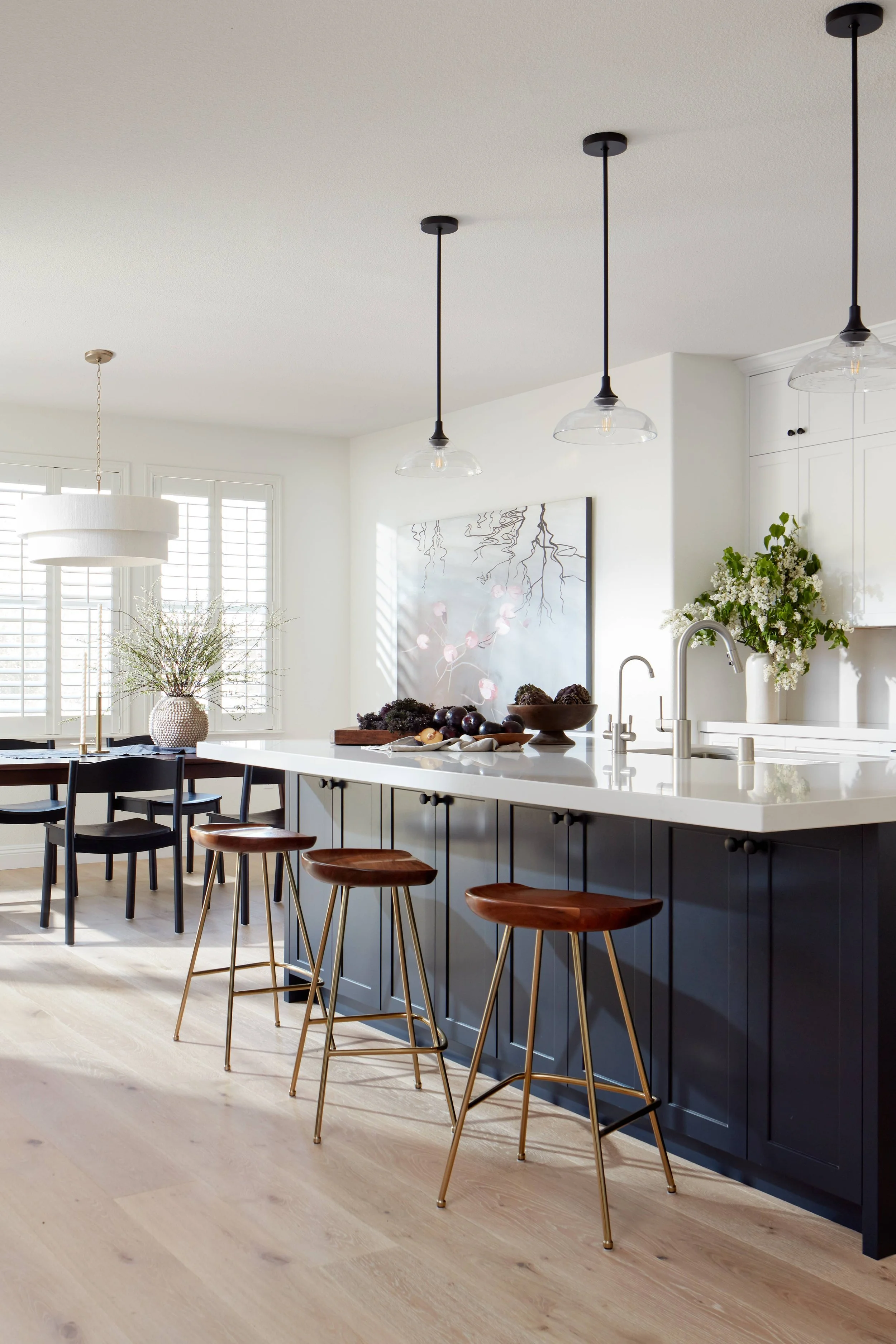Kitchen with custom cabinetry, walnut and gold stools, custom island color, glass light pendants, stone counters and backsplash, black accents