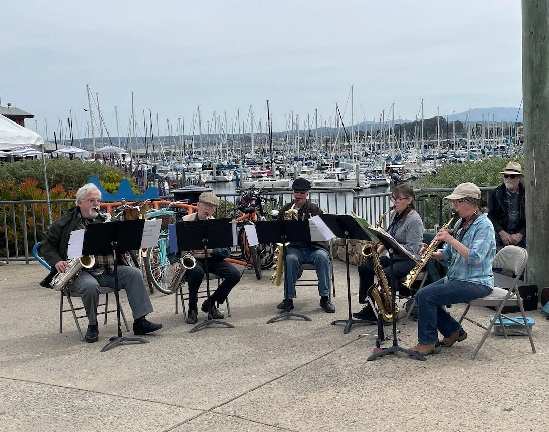 group of musicians playing with a conductor under a large white tenant