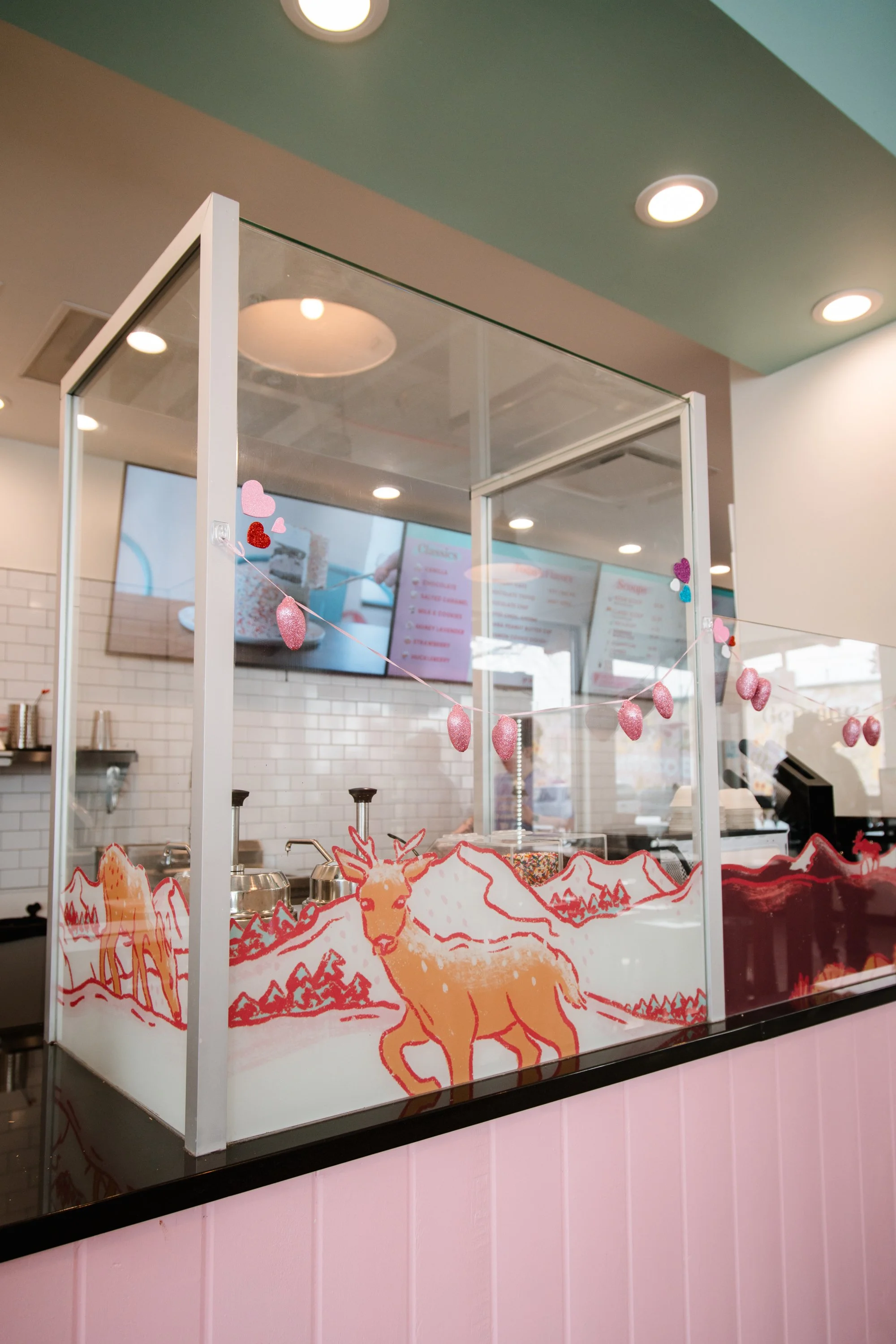 Custom ice cream counter window graphics with red and orange deer illustration on frosted vinyl inside Genuine Ice Cream in Bozeman, MT.