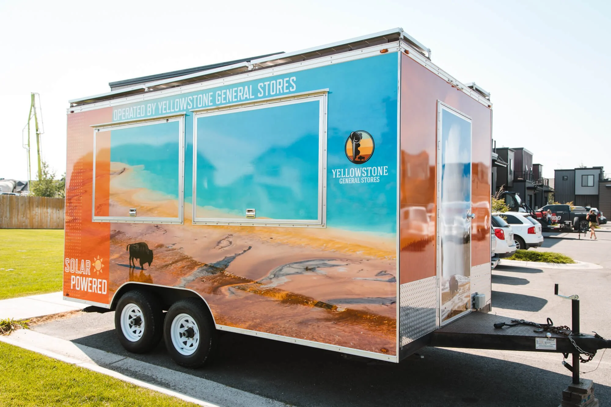 Side view of a trailer vinyl wrap with a photo of Grand Prismatic and a bison as the background as well as branding from Yellowstone General Stores