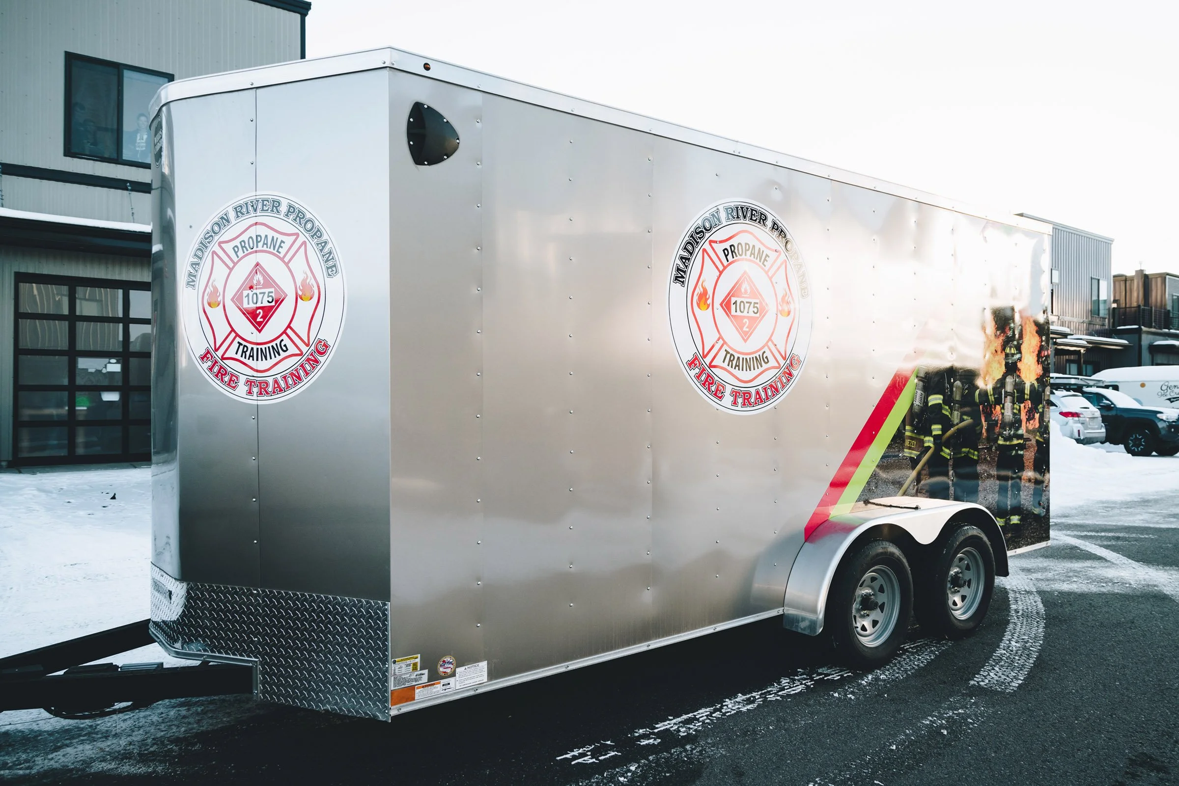 Branded trailer graphics for Madison River Propane Fire Training in Bozeman, Montana, with logo decals and partial fire training scene on metallic silver trailer panels. 