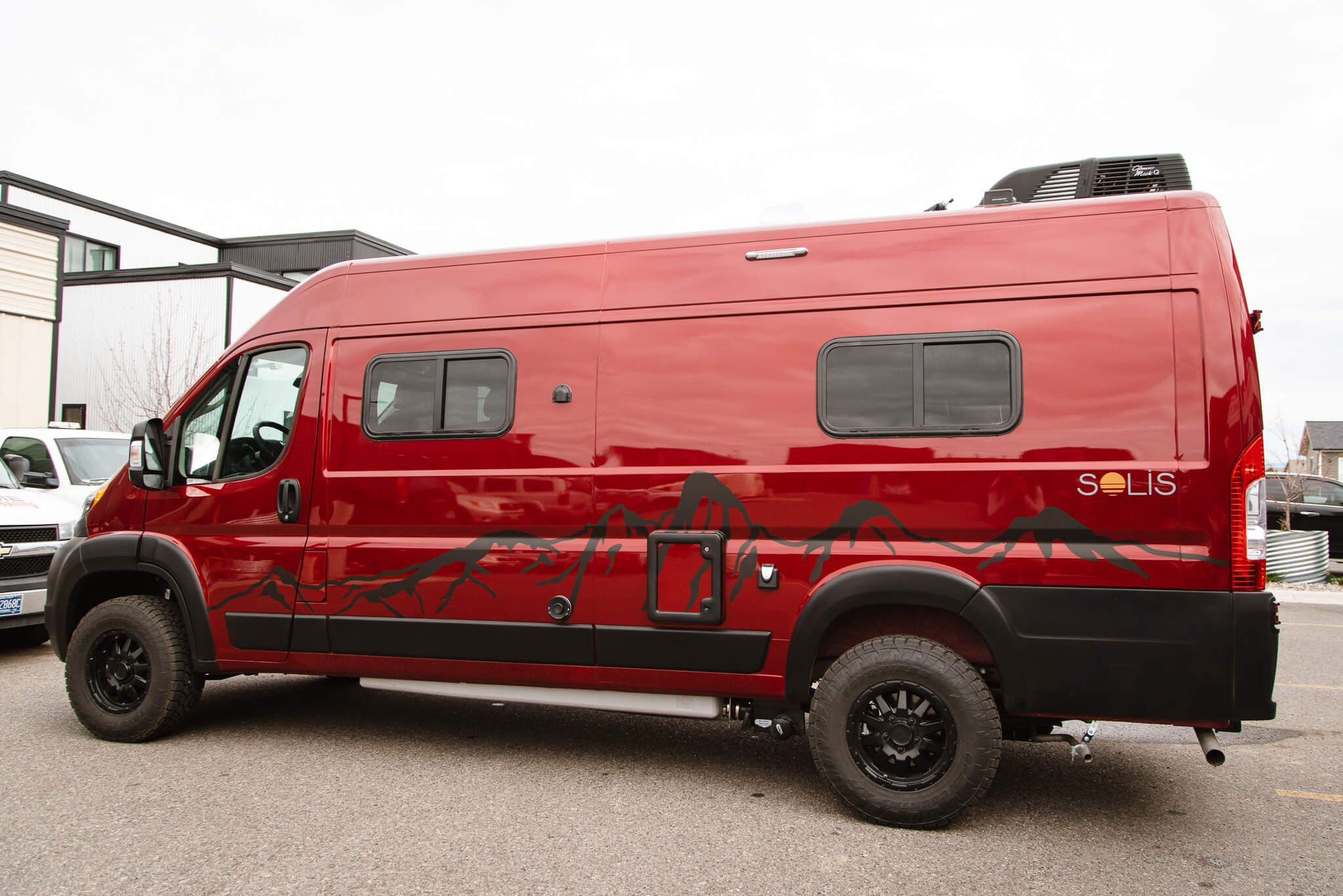 Subtle matte black mountain graphics running along the rocker panels of a maroon camper van