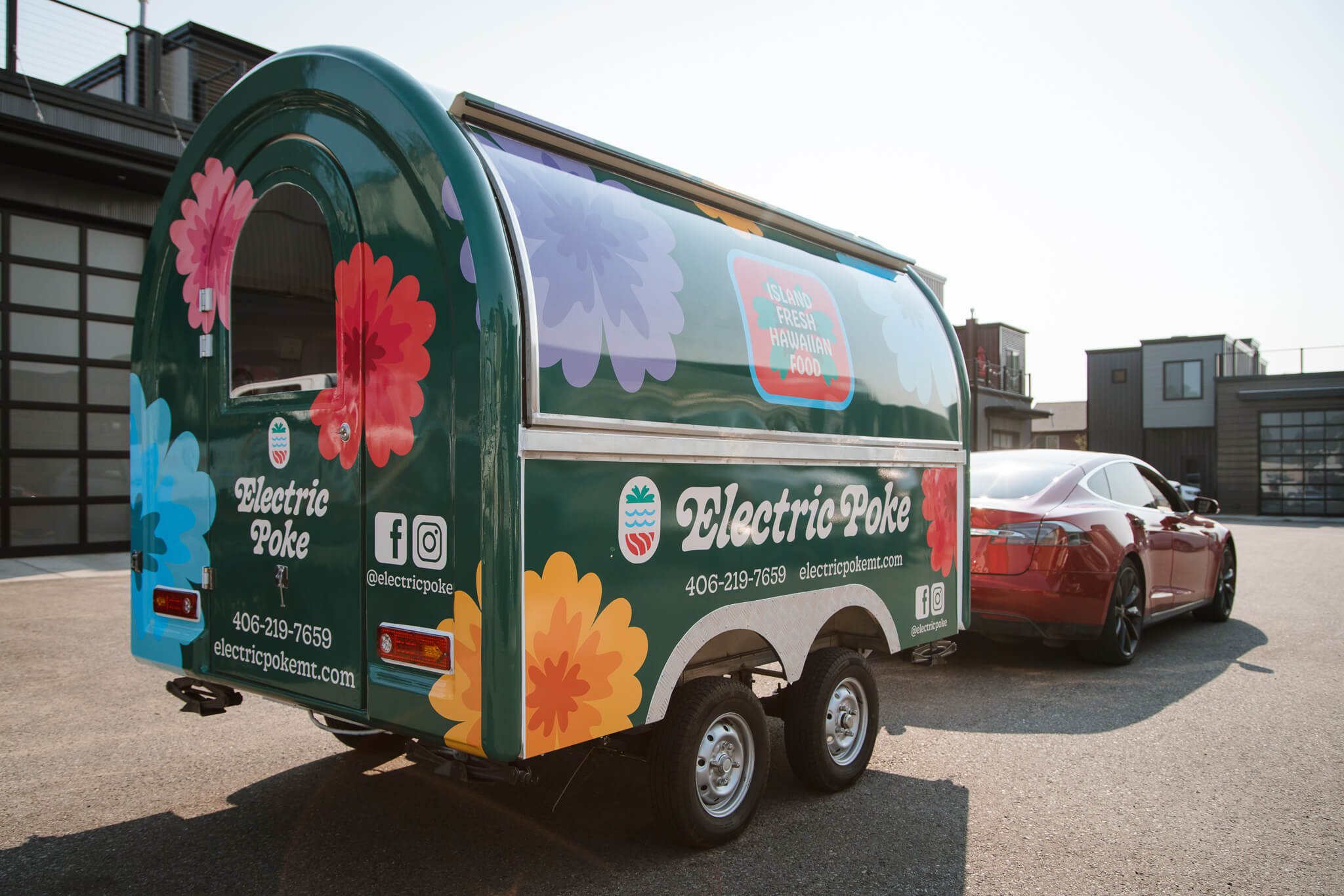 Full wrap for Electric Poke mobile food trailer in Bozeman, Montana, with large multicolored flowers and brand logo, showcasing a fun and approachable vinyl trailer wrap design.