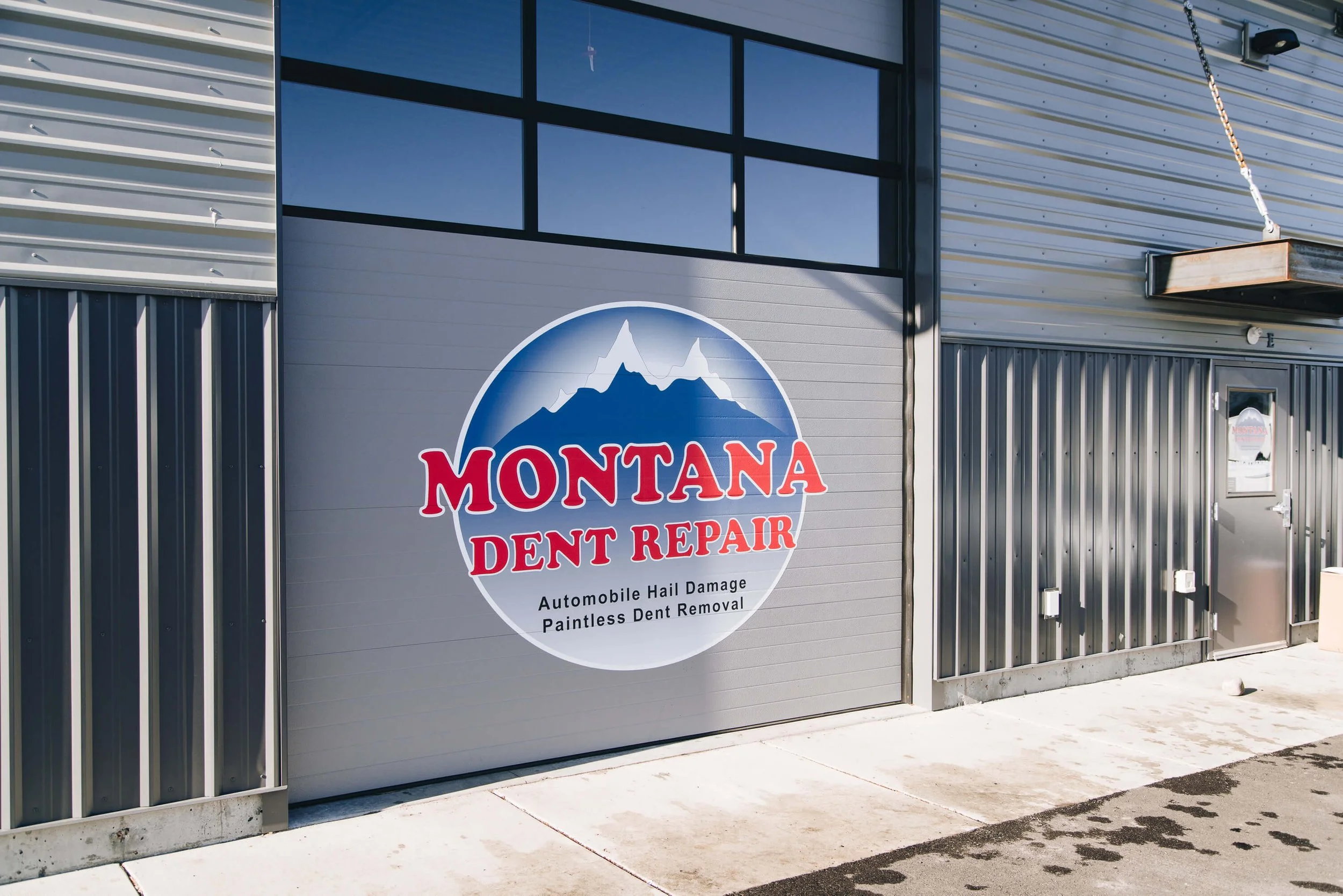 Montana Dent Repair building exterior with vinyl garage door logo.