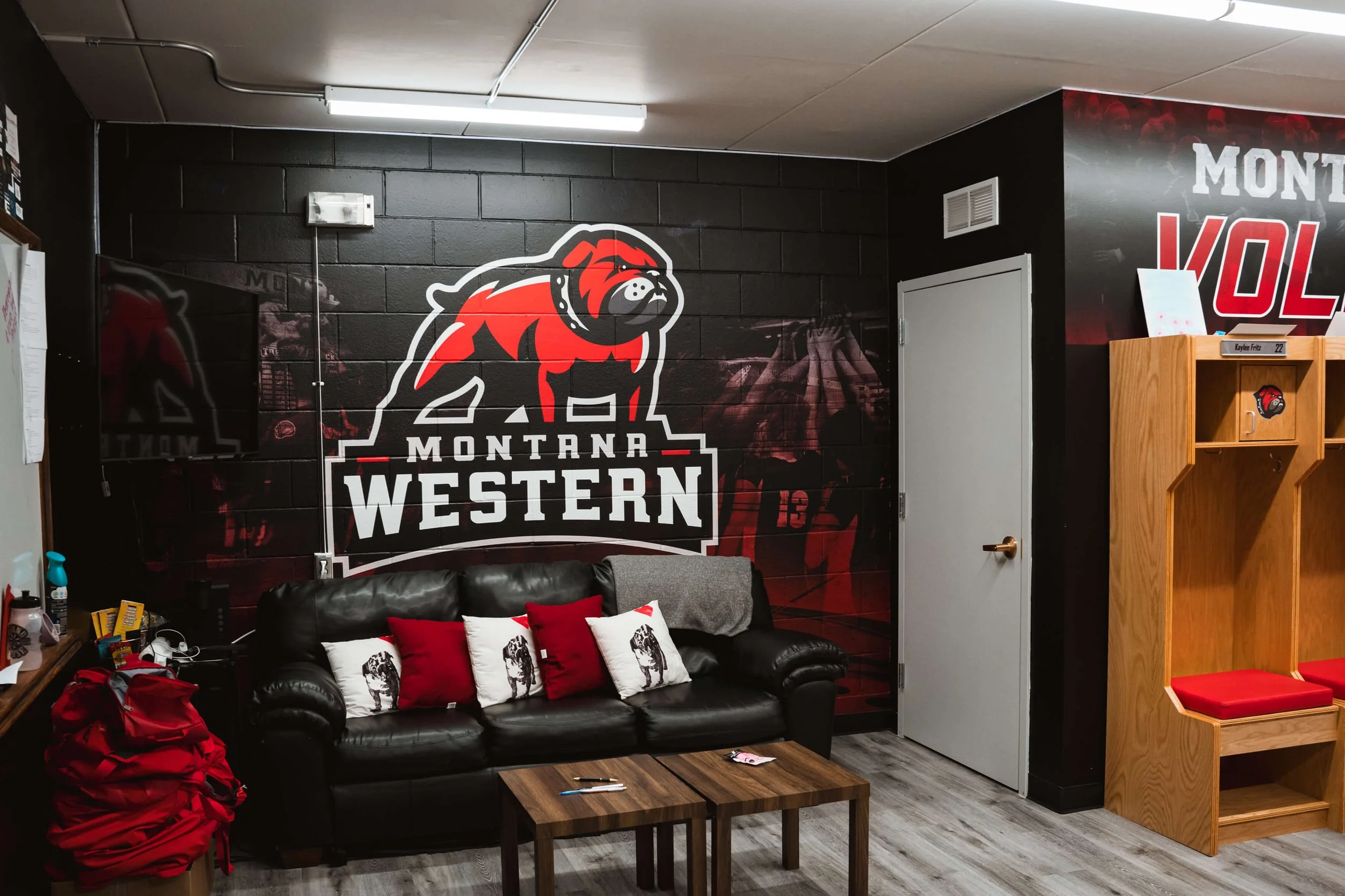 Athletic locker room wall wrap featuring the Montana Western bulldog mascot above a couch and lockers, creating a bold and inspiring team environment in Dillon, MT.