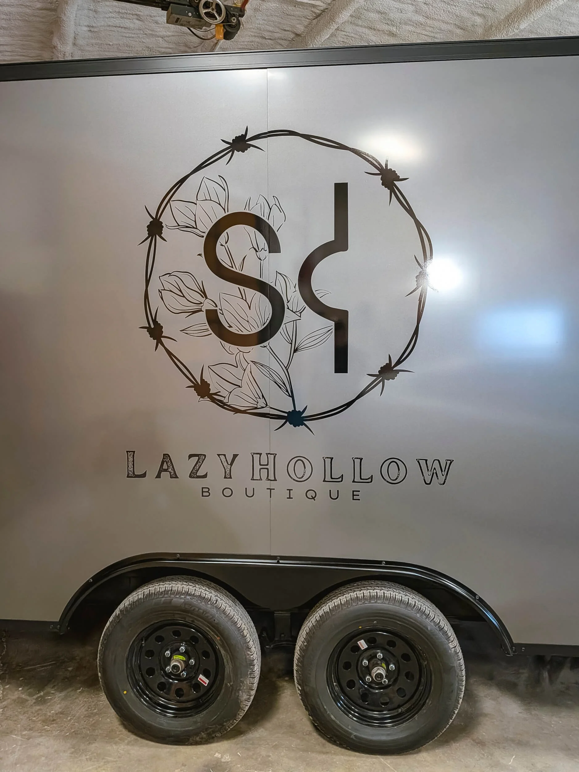 Lazy Hollow Boutique logo printed on clear vinyl centered over the wheel well of a trailer