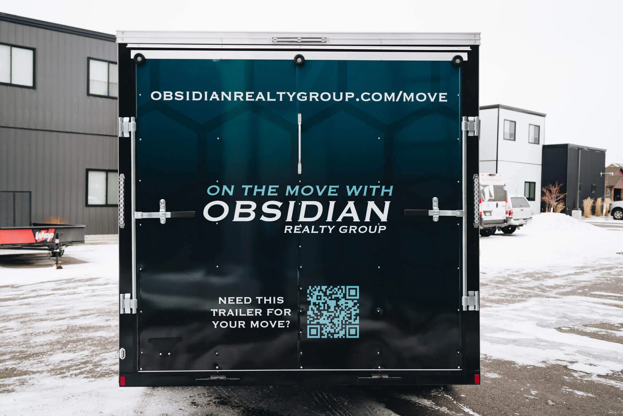 Rear view of an Obsidian Realty Group trailer wrap in Bozeman, Montana, featuring trailer graphics with branding, URL, QR code, and bold real estate messaging for mobile advertising.