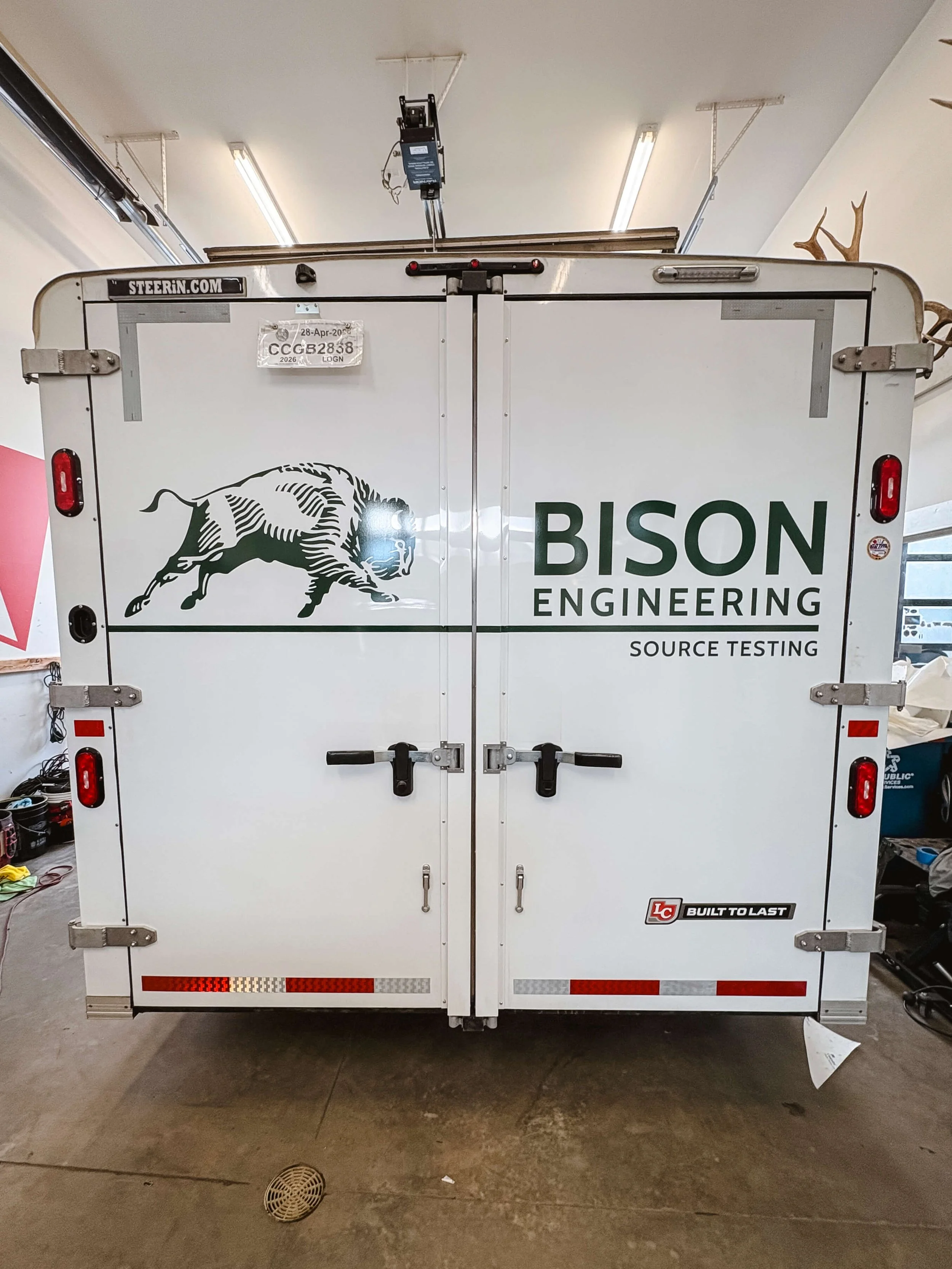 Split doors on the back of a trailer with a green running bison and Bison Engineering text 