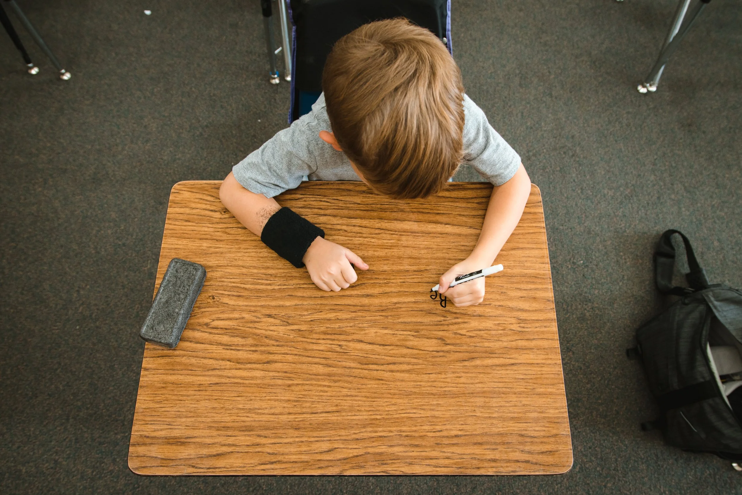 Overhead view of a student beginning a writing exercise on a clear dry erase desk wrap.