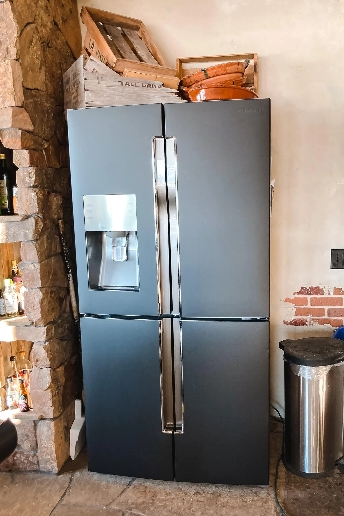 Matte black refrigerator with chrome handles and a built-in water dispenser, wrapped in a sleek custom vinyl wrap to match modern interior decor.