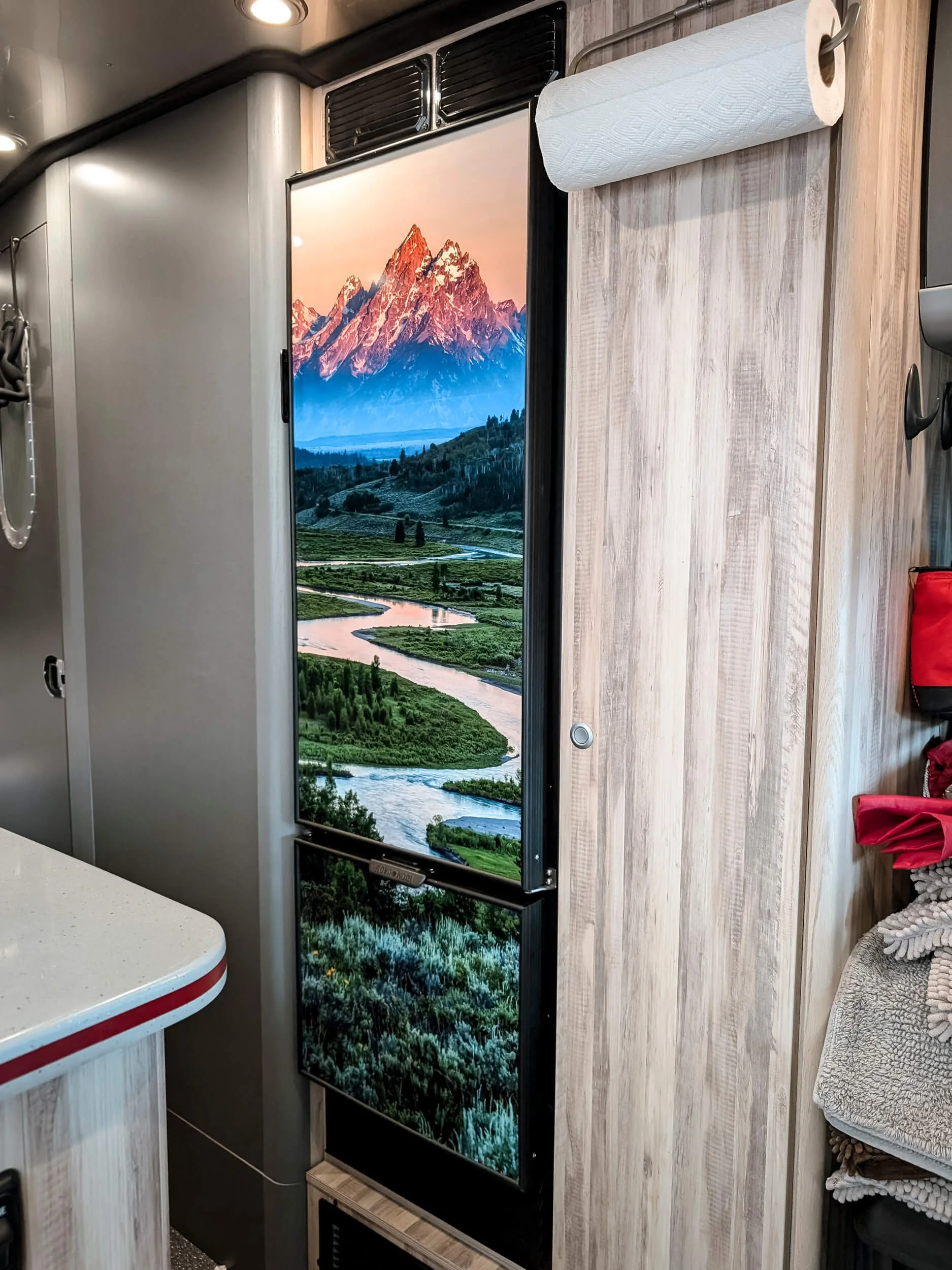 A camper van fridge door wrapped with a full color photograph from Grand Teton National Park featuring the mountains and river at dawn