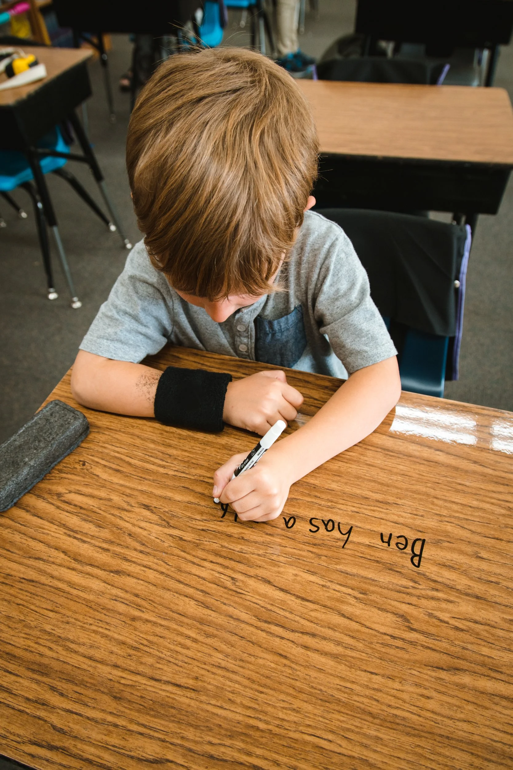 Student practicing handwriting directly on a clear dry erase desk covering.