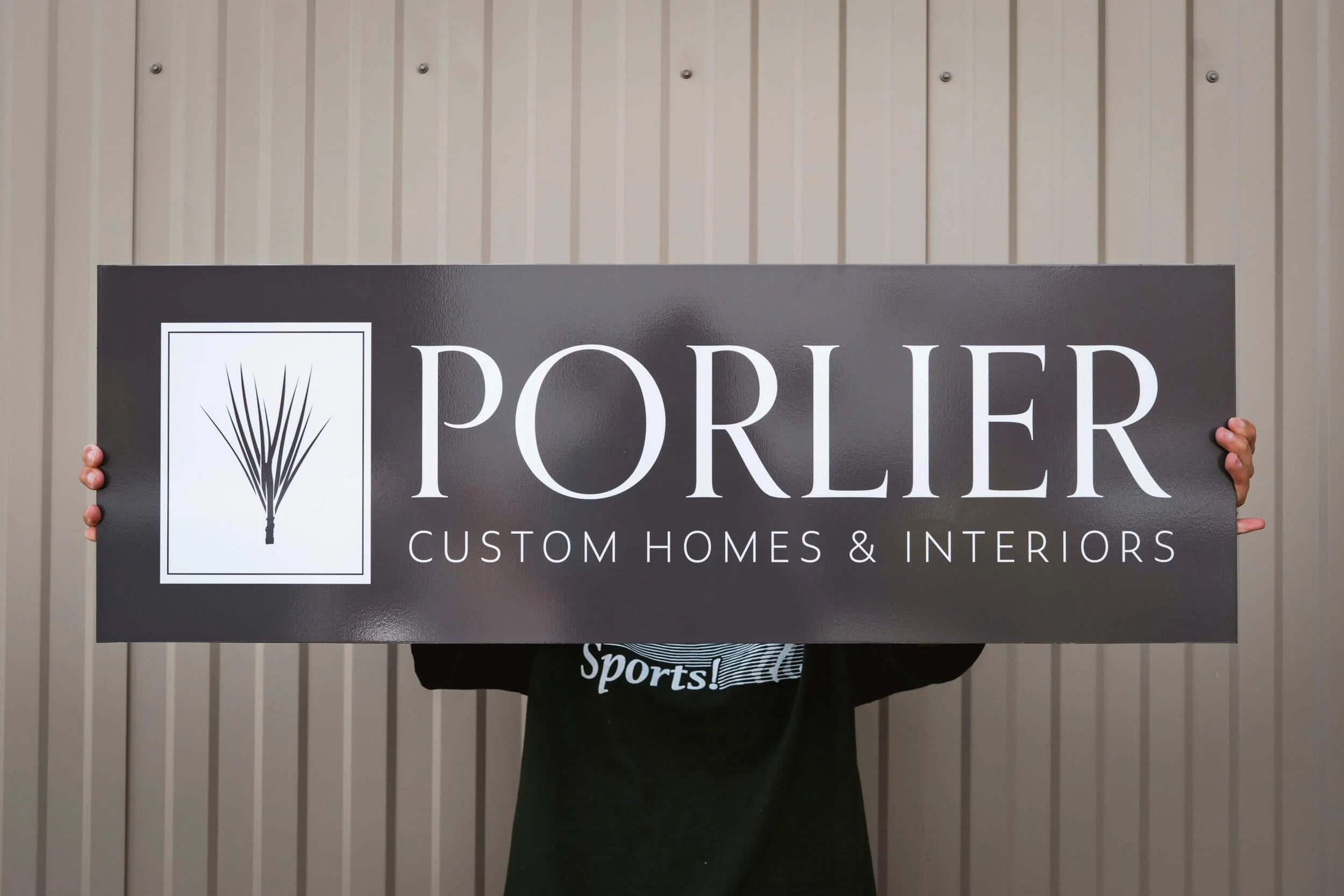 A rectangular Bozeman custom sign for Porlier Custom Homes featuring white text and logo on a dark grey background, including contact information and website URL.