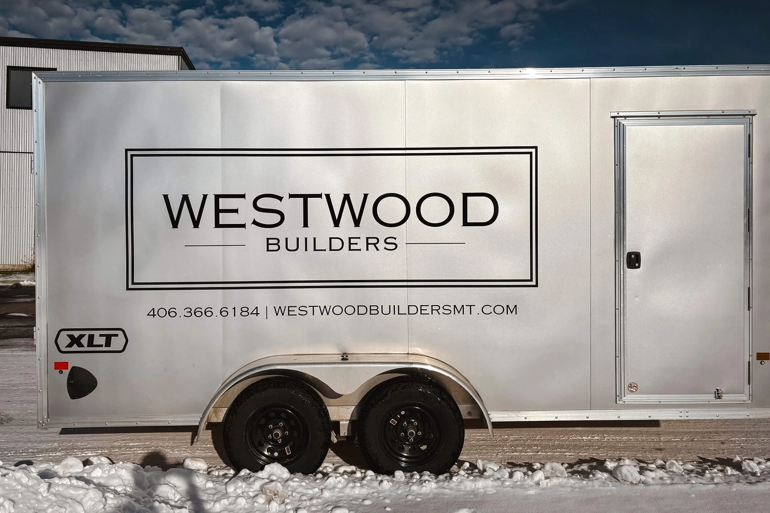 Simple black logo and contact info for Westwood Builders on a silver trailer