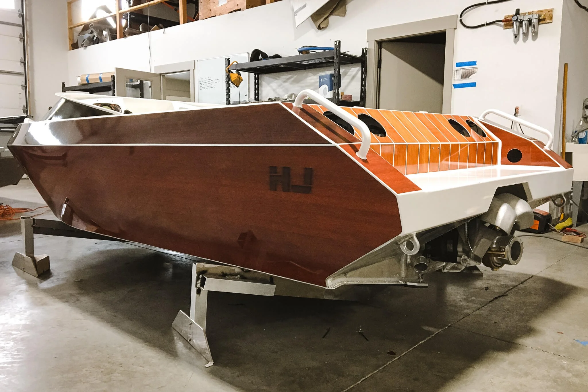 Rear angle of a metallic jet boat with a rich faux woodgrain custom vinyl wrap and clean white borders, staged indoors in Bozeman, MT.