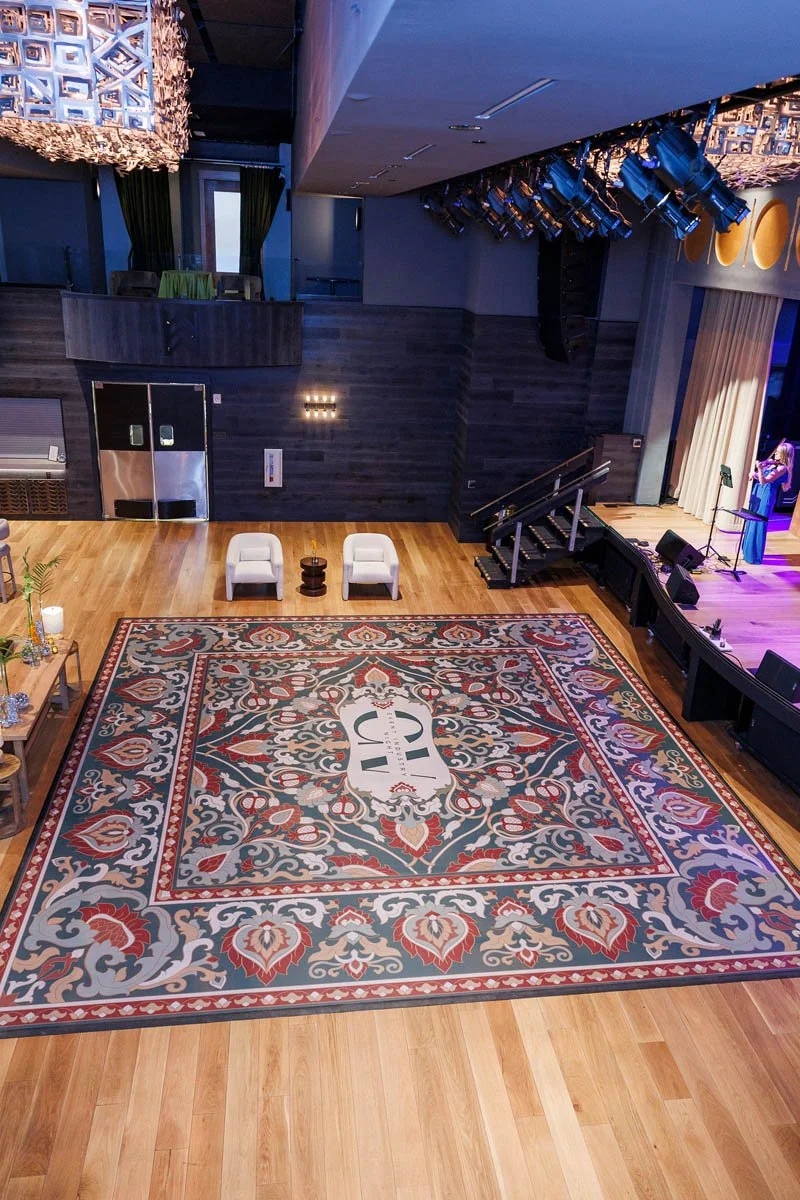 Overhead view of a full custom dance floor wrap with floral rug-inspired graphics at the Armory Hotel in Bozeman. This bold 21’ x 21’ dance floor vinyl wrap was donated by The Wrap Agency. Photo by Kristen Rose Photography.