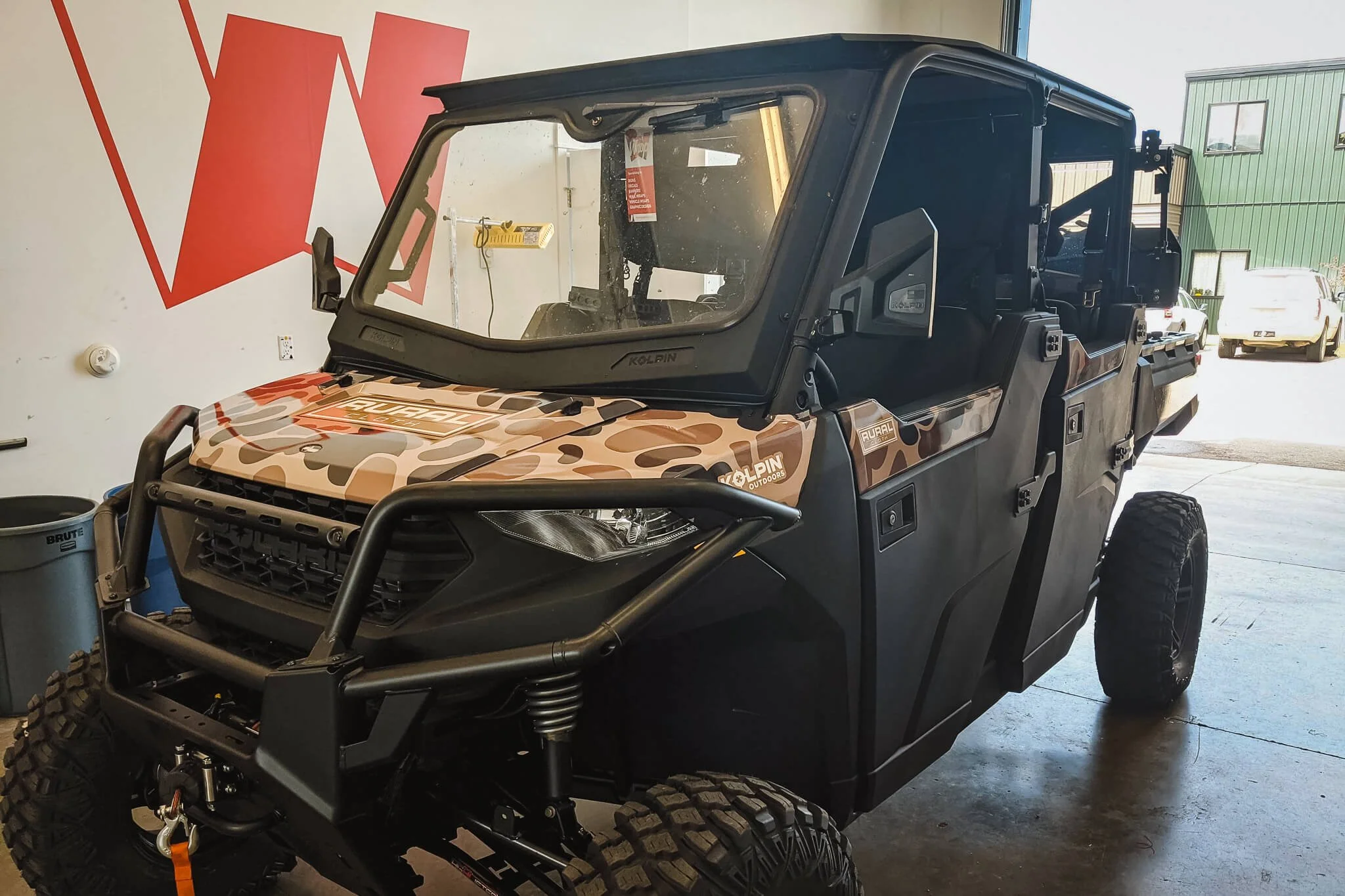 Full camo pattern wrap applied to a side-by-side utility vehicle, combining rugged aesthetics and branded elements. Custom vinyl wraps for utility and recreation vehicles.