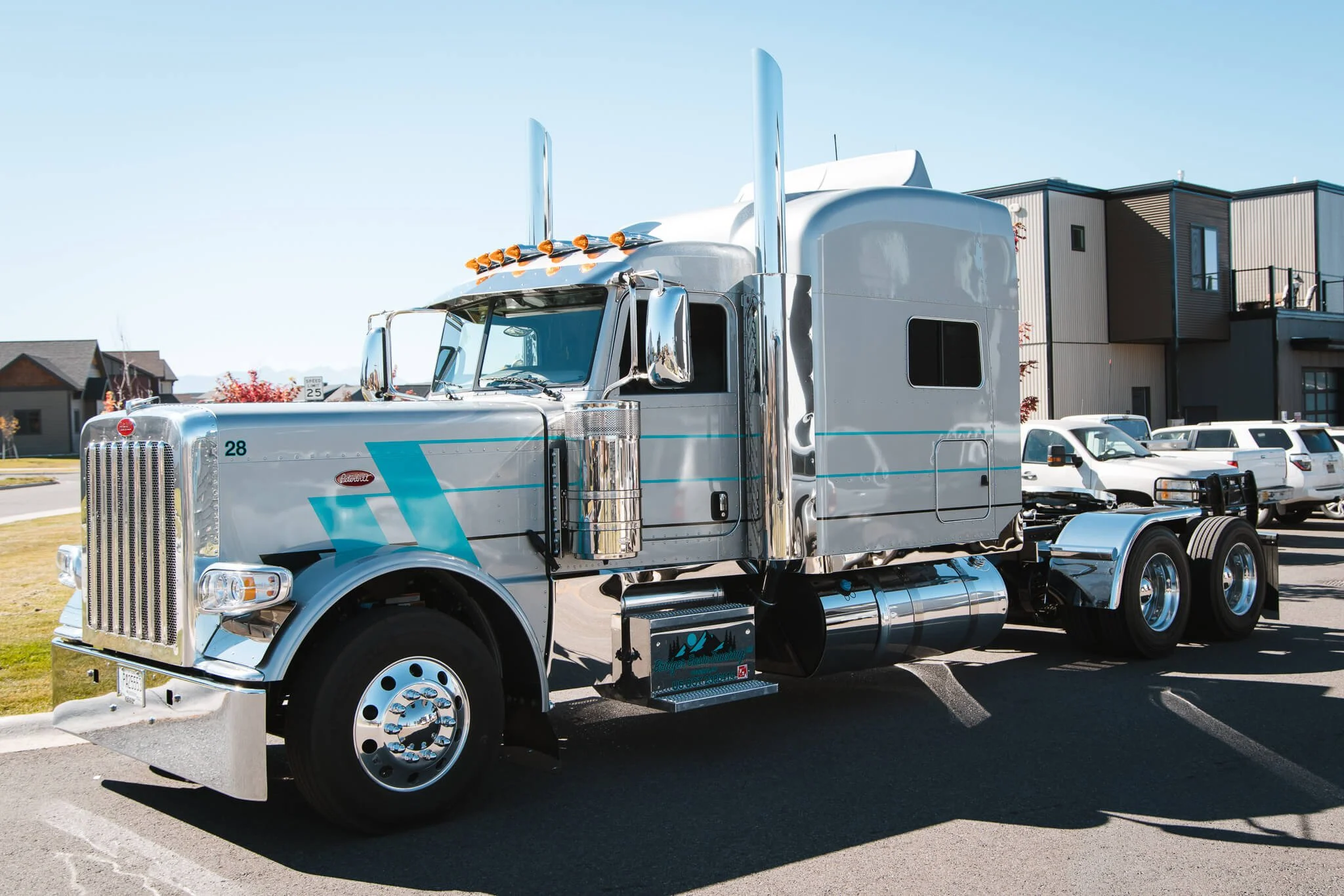 Side view of a chrome semi truck with metallic blue and gray angled striping, finished with a glossy custom wrap that enhances the vehicle’s size and sleek lines. Location: Bozeman, MT.