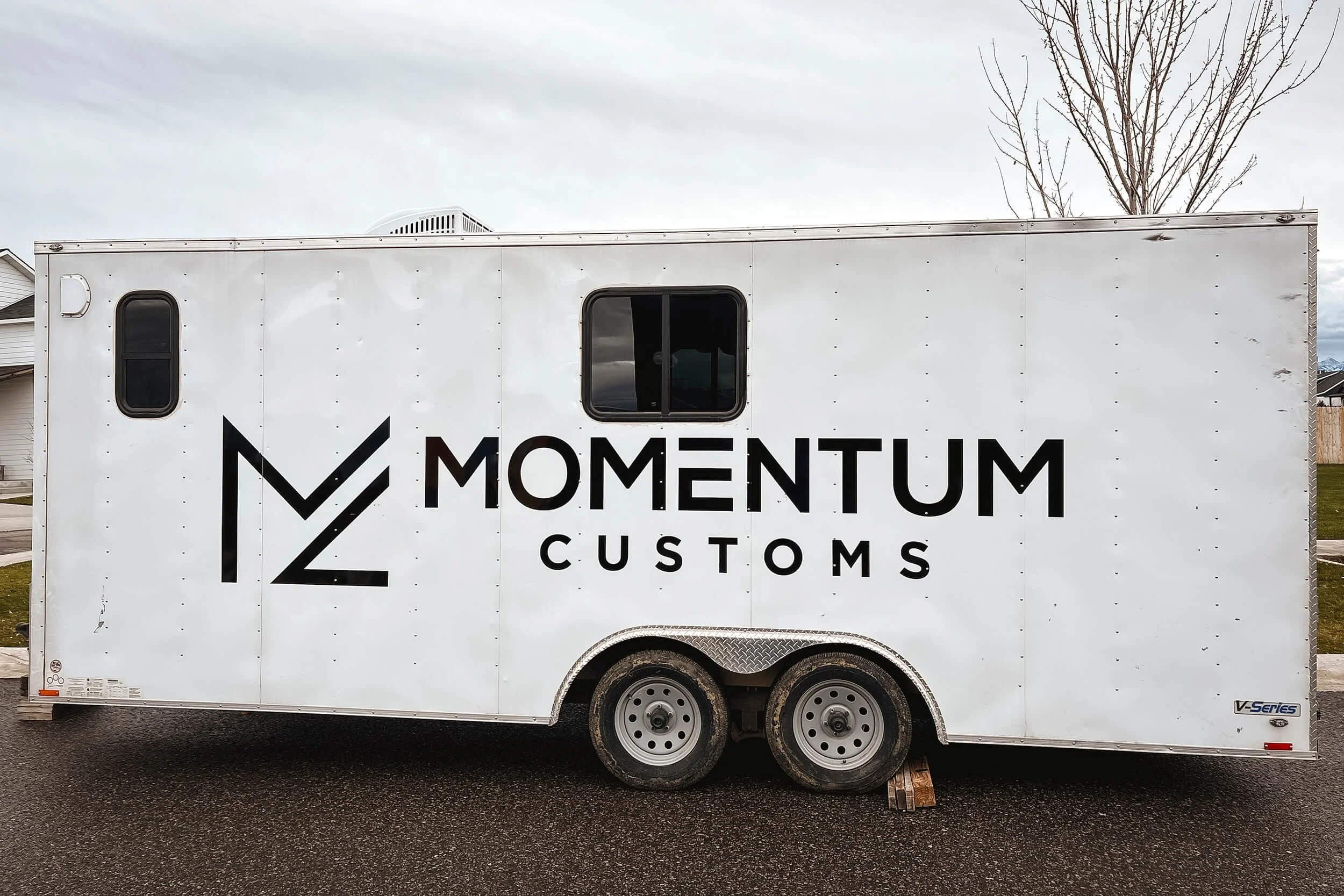 White trailer with a black vinyl logo for Momentum Customs
