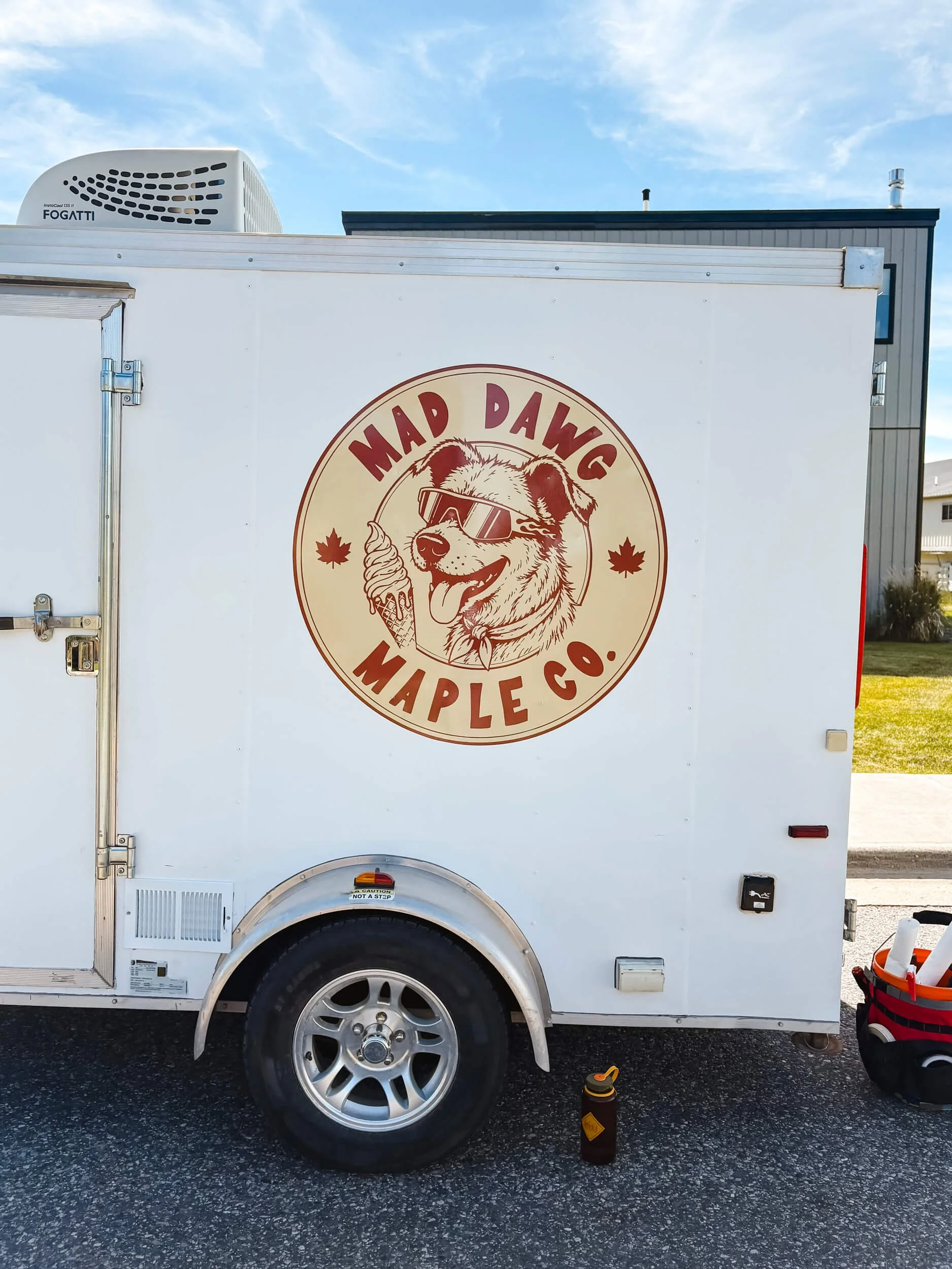 Logo of a dog with an ice cream cone for Mad Dawg Maple Co. on a white trailer