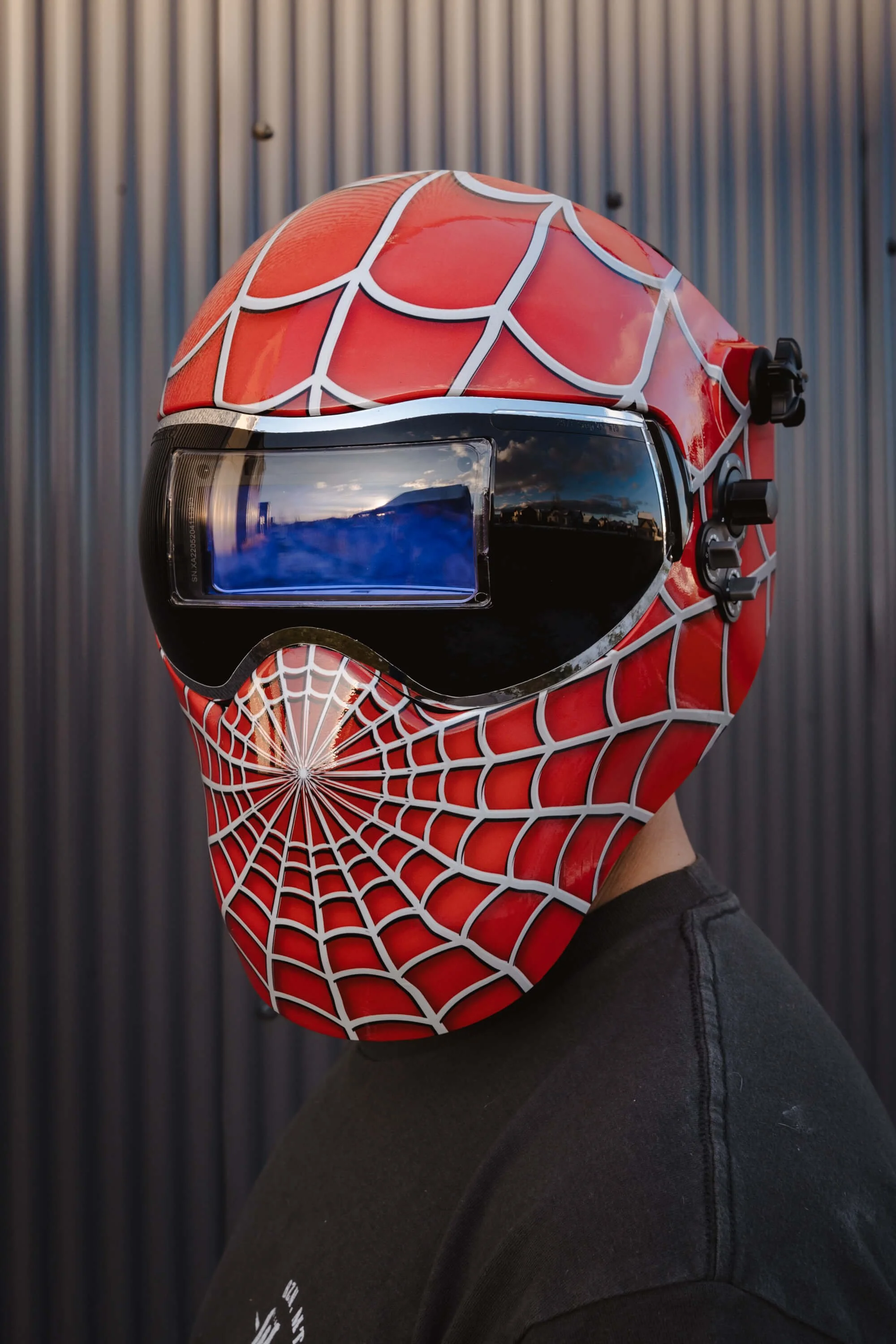 Custom vinyl wrap transforming a welding helmet into a Spider-Man-inspired design, showcasing the versatility of vinyl graphics for personal protective gear.