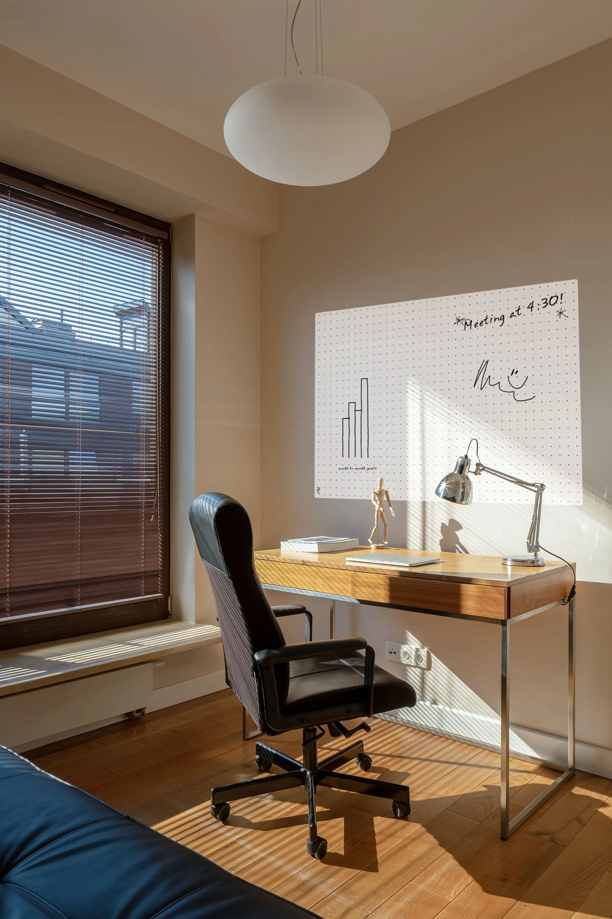 Grid-patterned dry erase wall covering with handwritten notes and a bar chart above a home office desk.